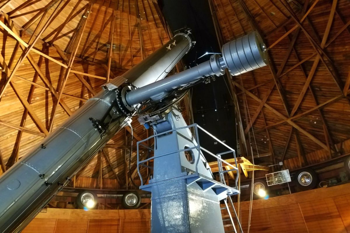 Telescope peering through Lowell Observatory, Flagstaff, Arizona, from the inside, wooden doom opened for telescope, nights sky through the opening
