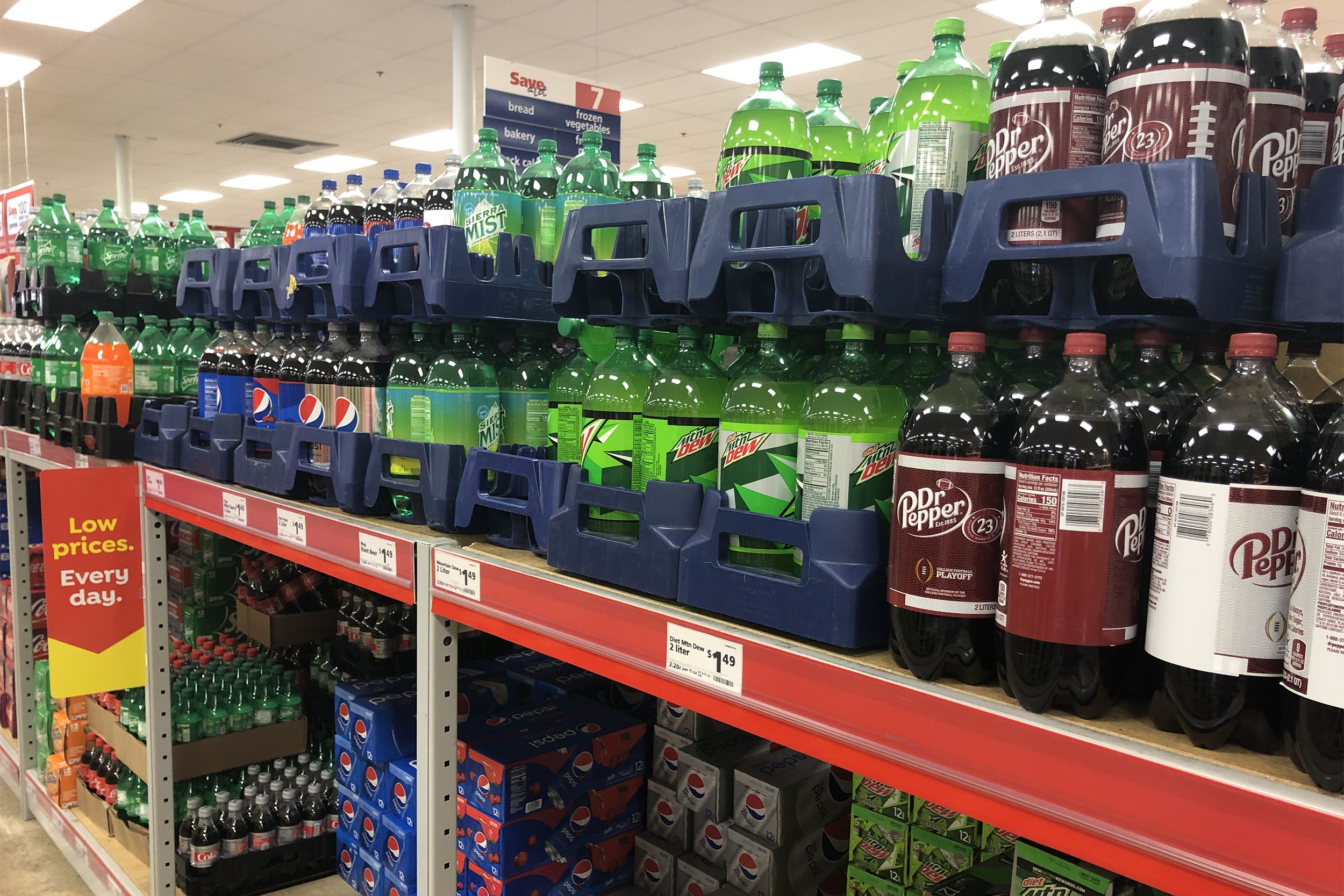 Various soft drinks in soda aisle for sale at Save A Lot, cans on the bottom shelf and 2-liters on the top shelf