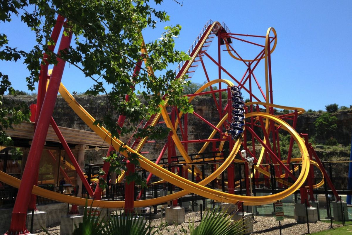 Wonder Woman Golden Lasso Coaster, Six Flags Fiesta Texas, San Antonio, cart riding on it, trees in the left foreground, with a blue sky on a sunny day