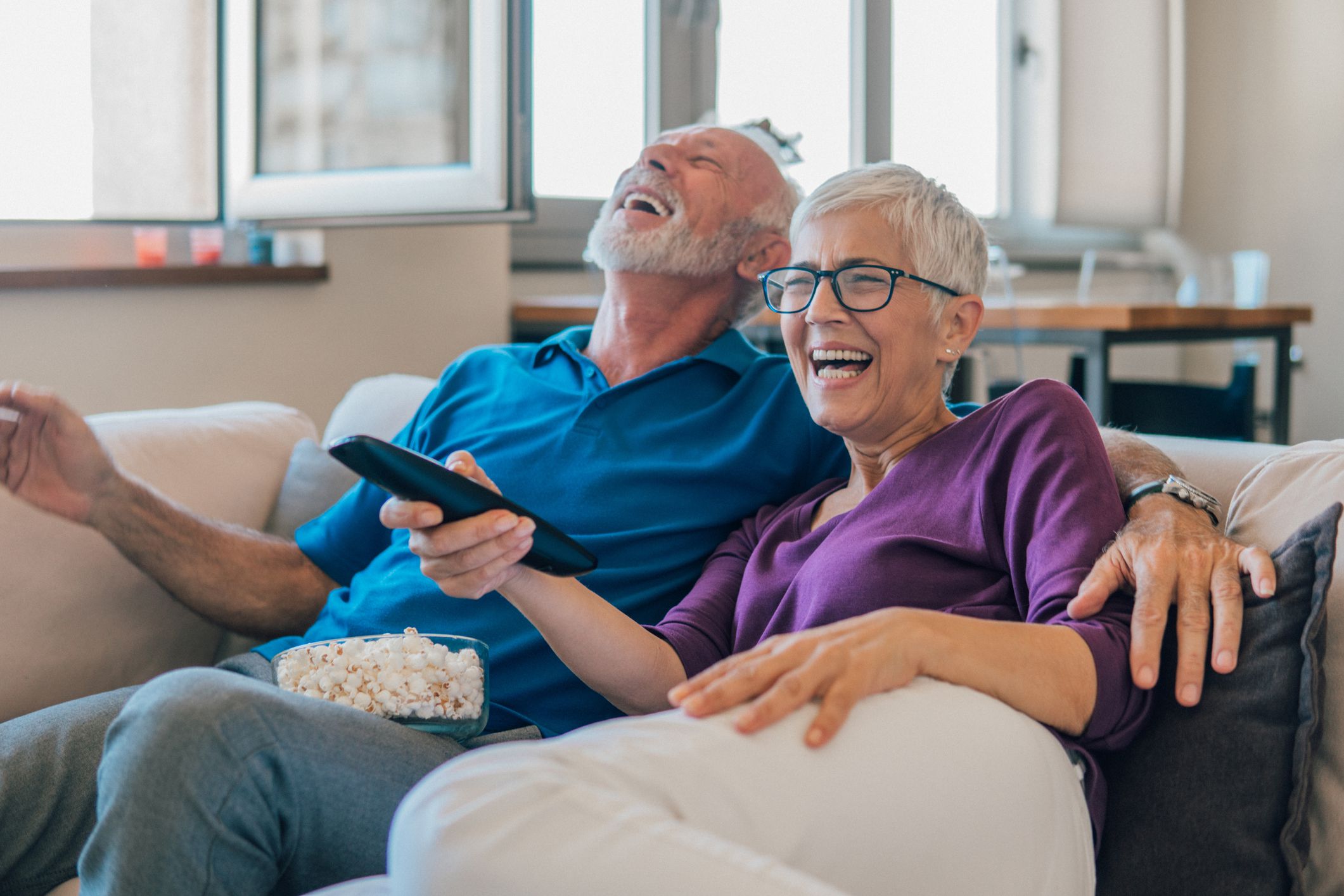 Elderly couple resting with popcorn and remote control in their hands