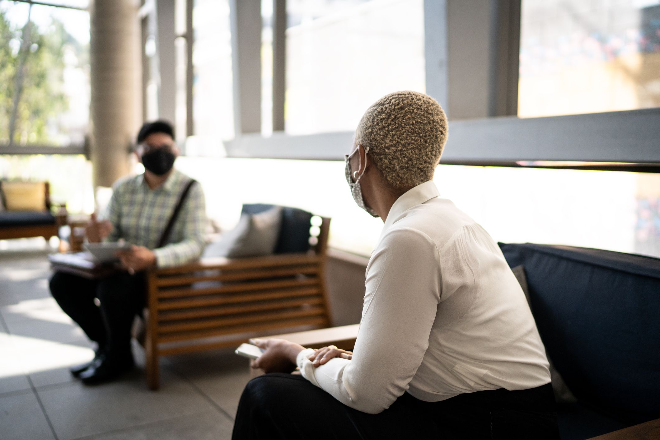 Coworkers talking on social distancing at work - with face mask