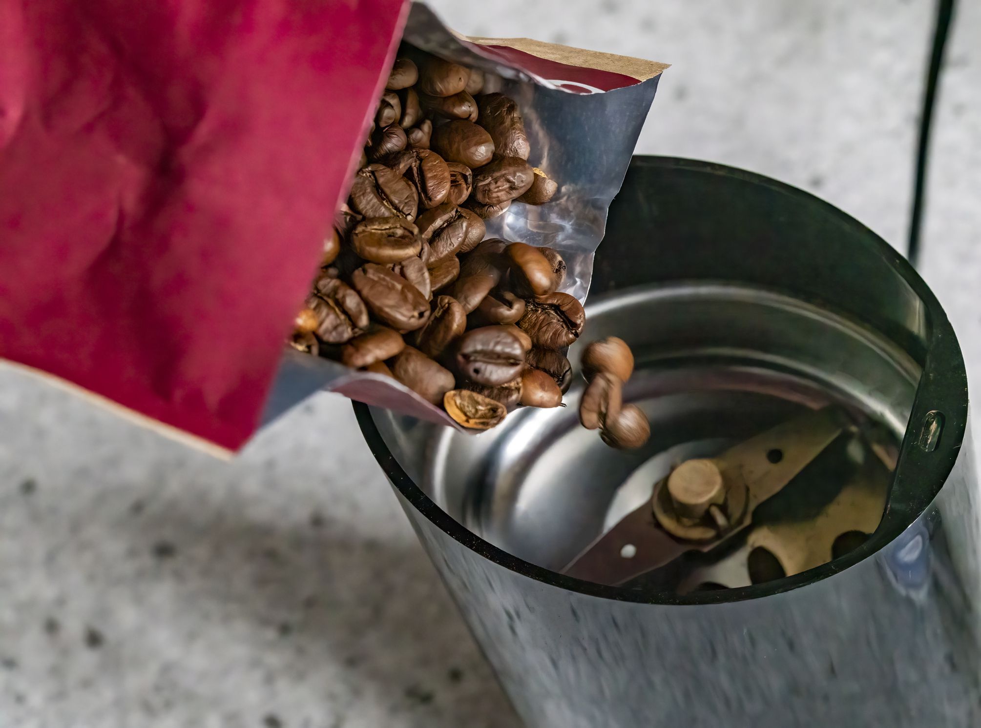 Coffee beans being poured into a coffee grinder.