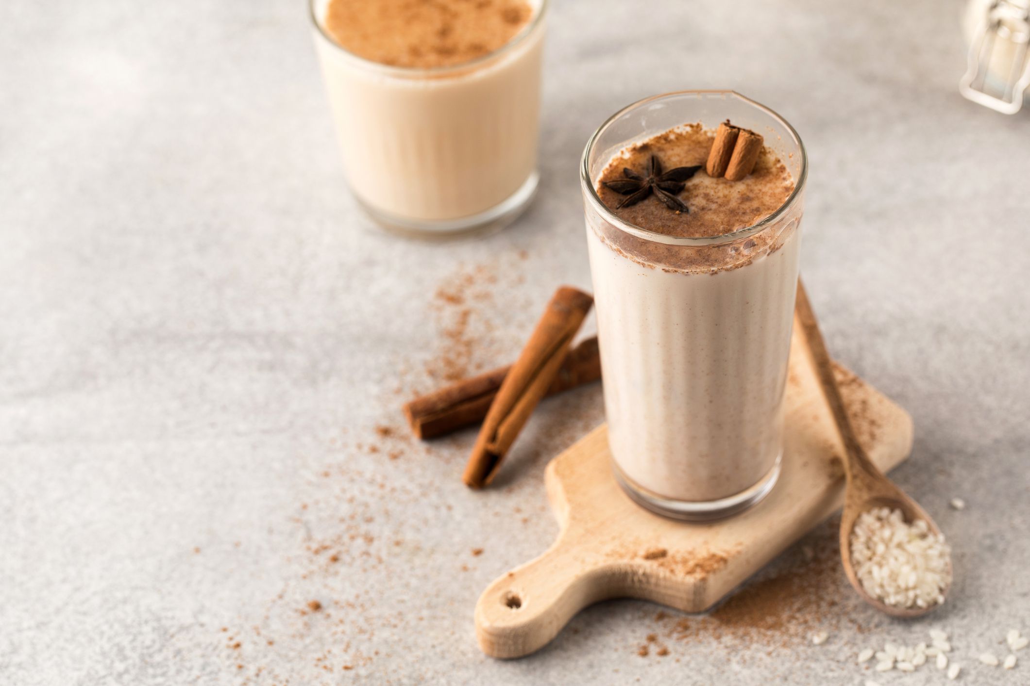 Cold drink based on Horchata rice in a glass on a wooden board with cinnamon sticks on a light background.Vegetarian soft drink, national cuisine.