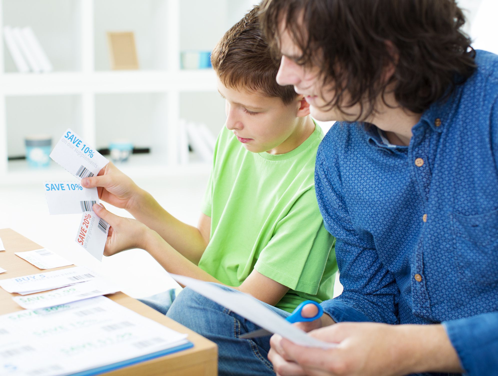Mother and father with son making shopping list and cut coupons for shopping. Selective focus to little boy smiling face. Couponing Concept. *Generic Coupons