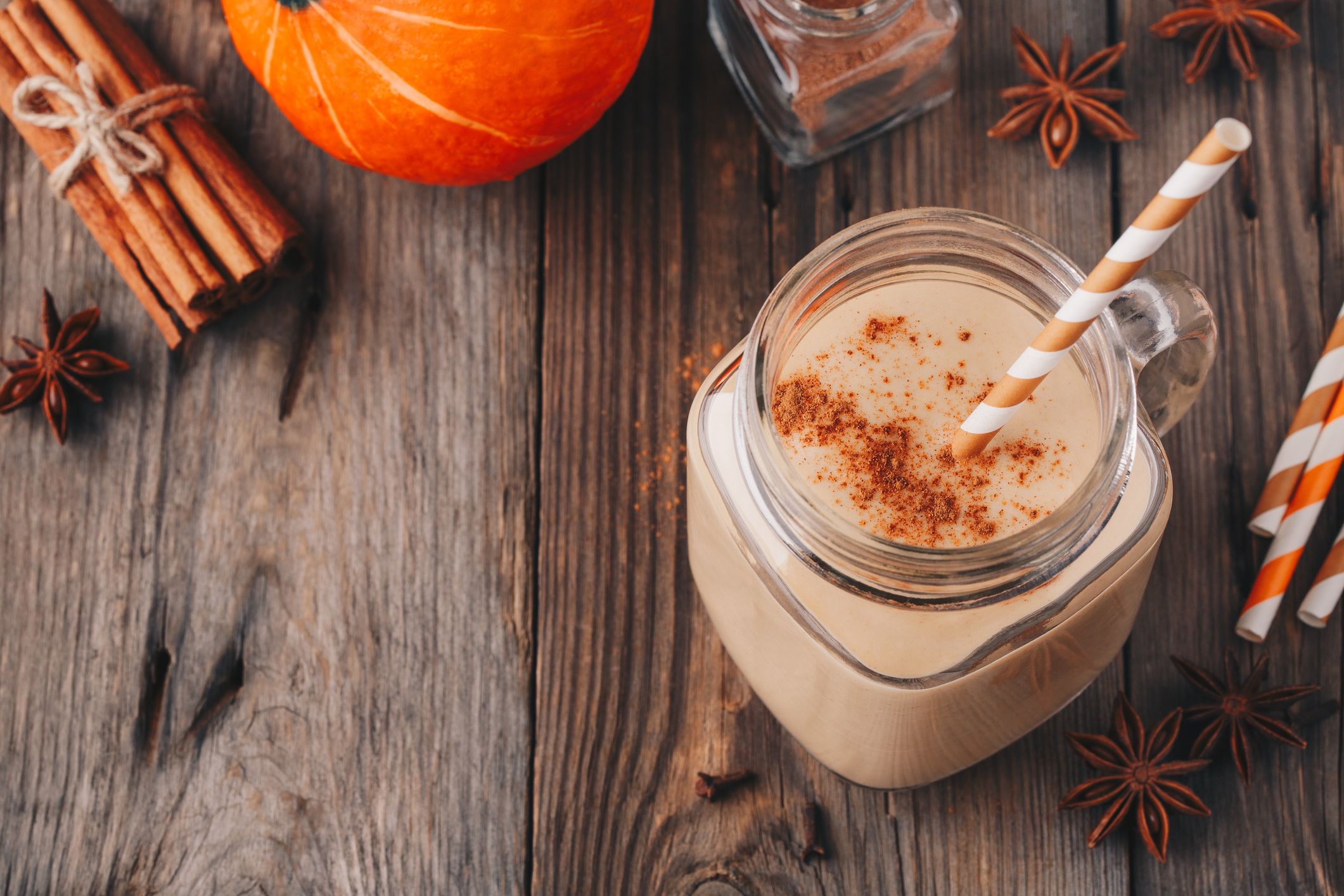 Pumpkin pie smoothie with cinnamon in mason jar on wooden rustic background