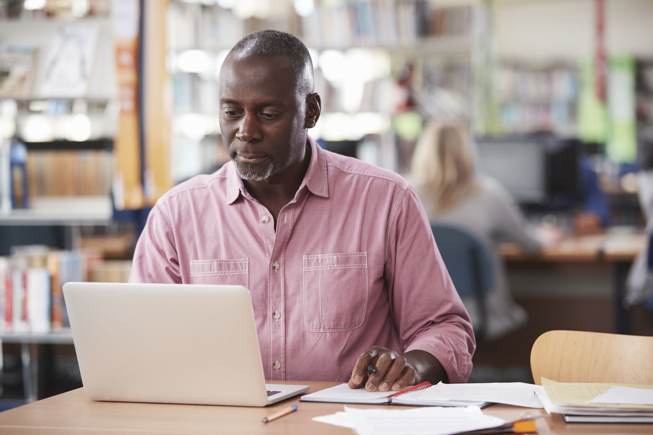 middle-aged man researching with laptop at library