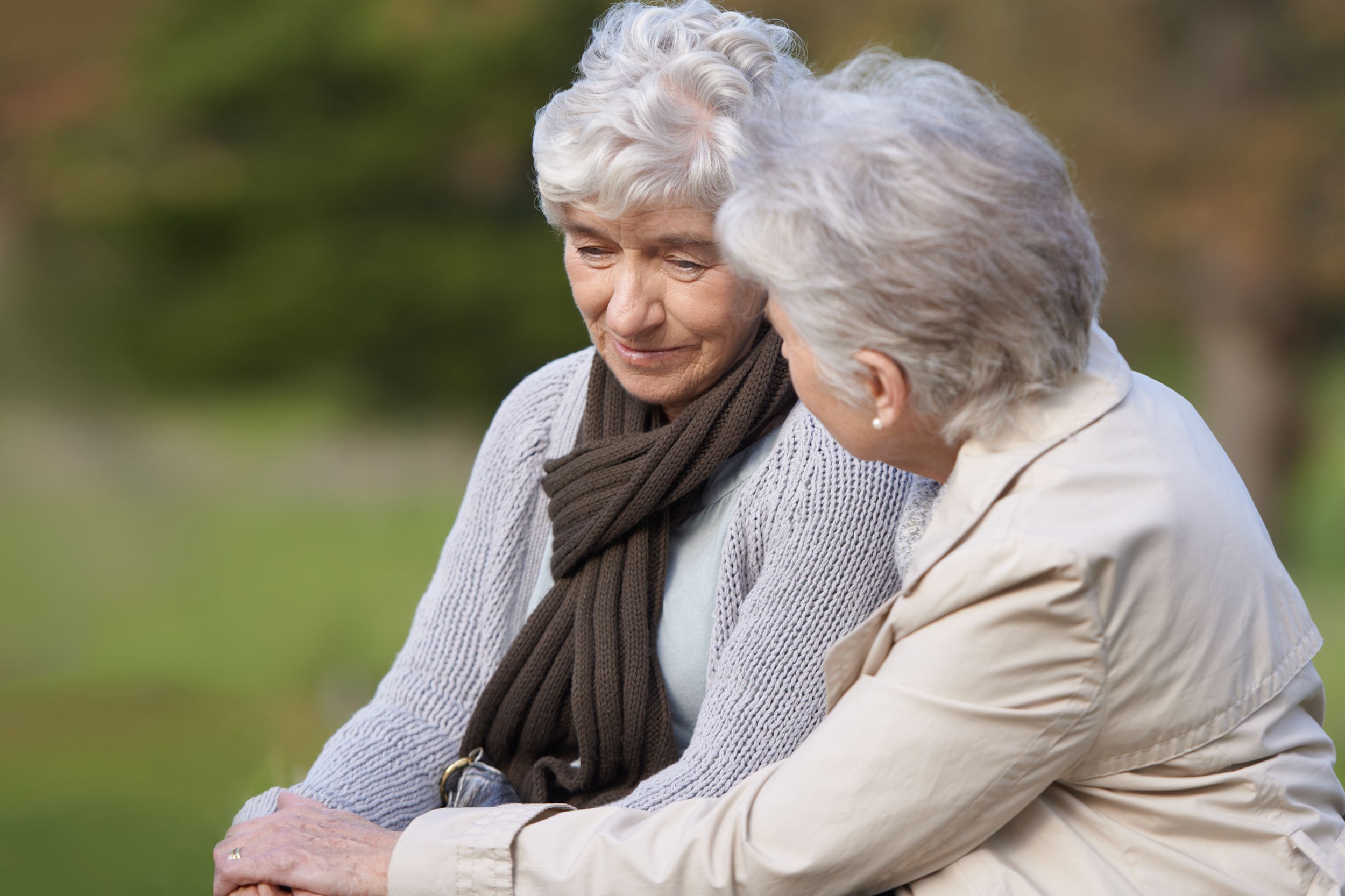 senior woman comforting her friend over loss while sitting outside