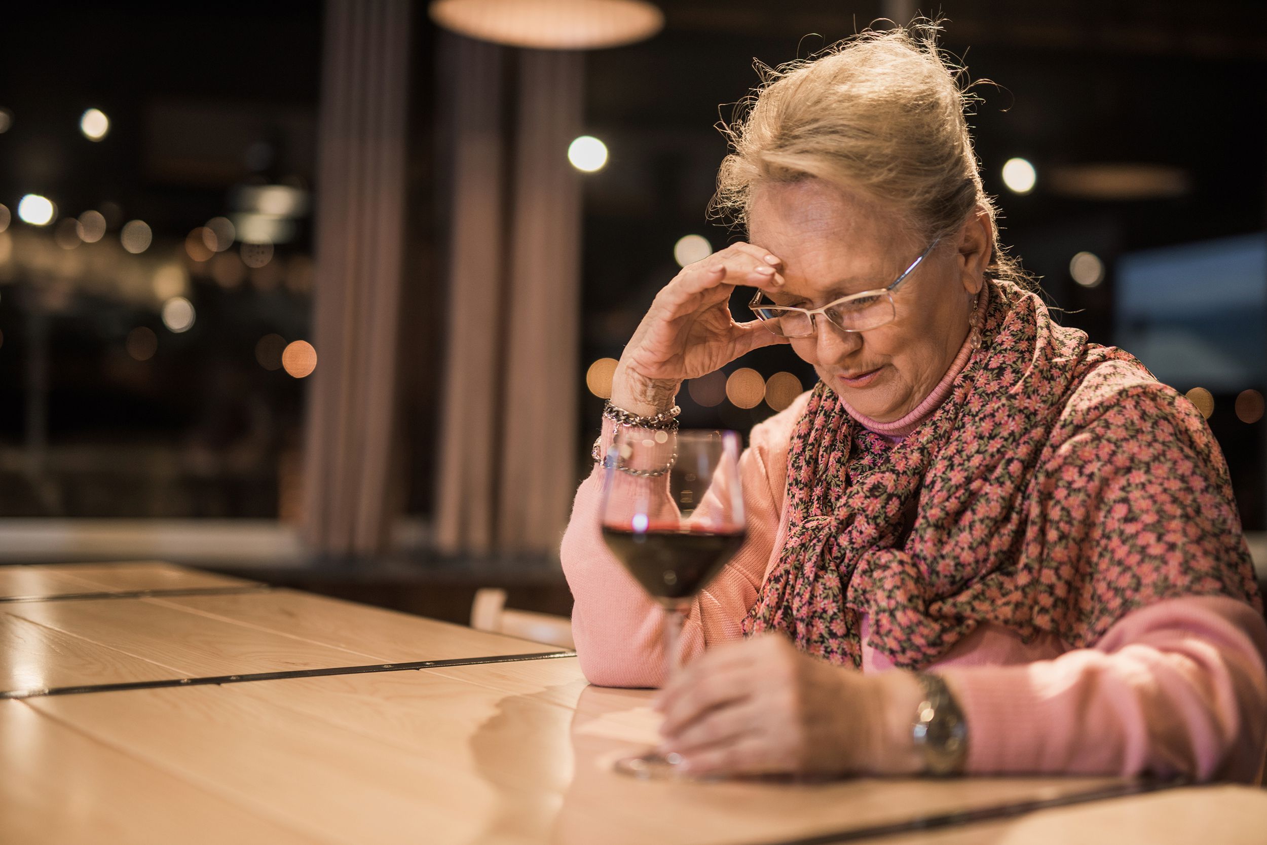 senior woman at restaurant alone with a glass of wine