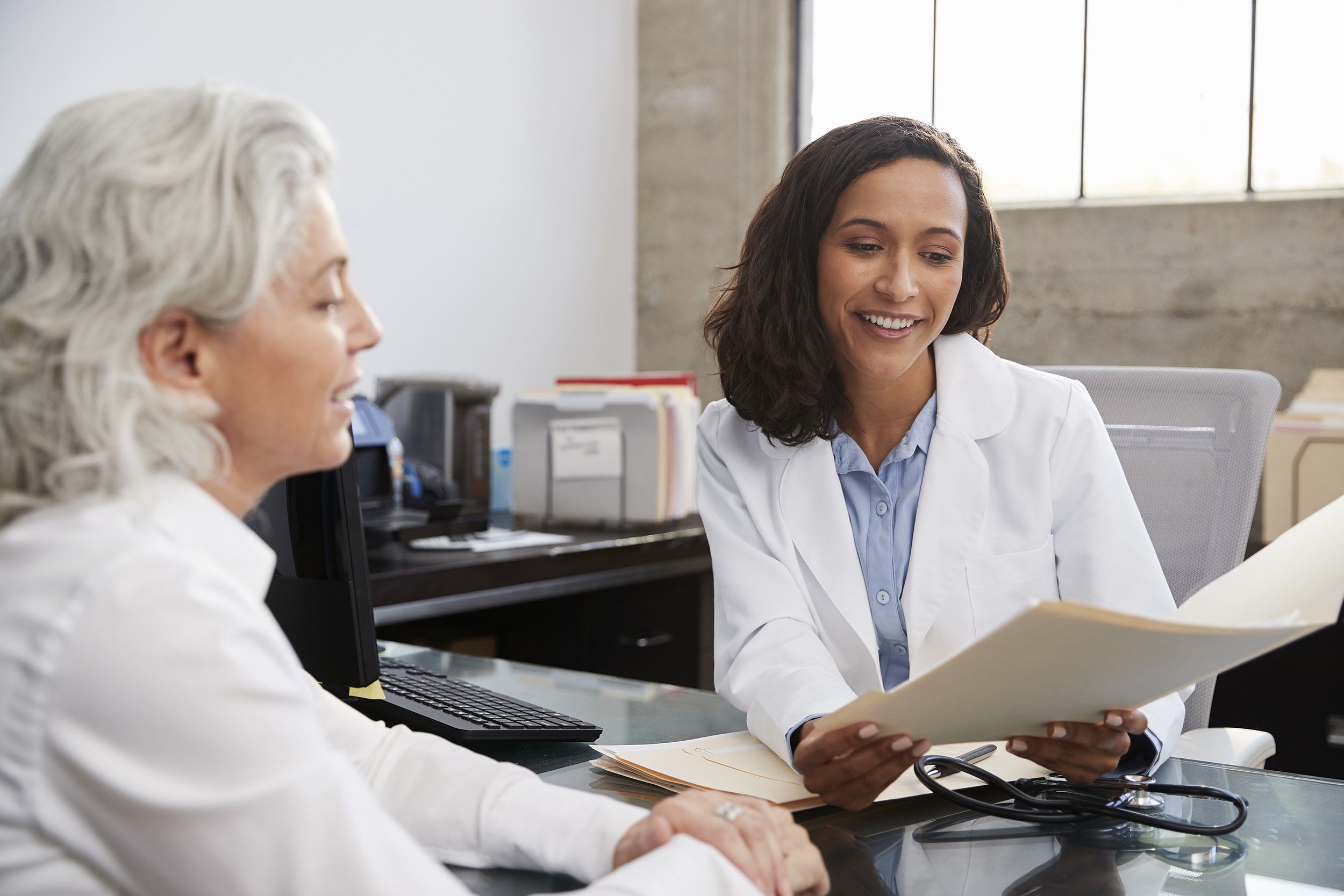 smiling female doctor in consultation with senior patient