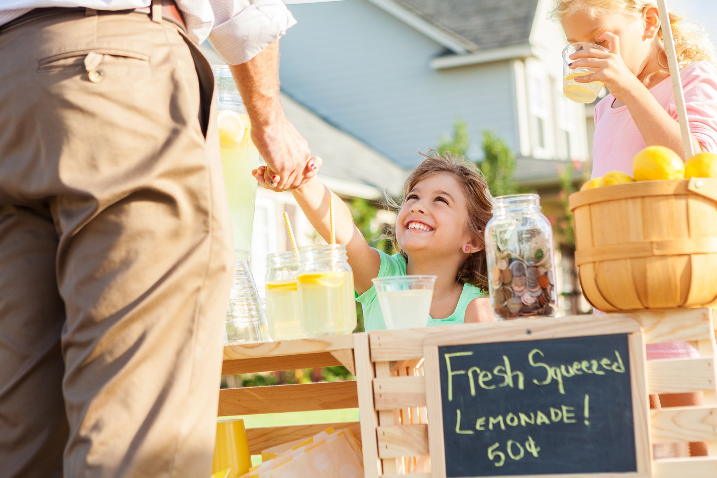 happy girl sells lemonade to a customer