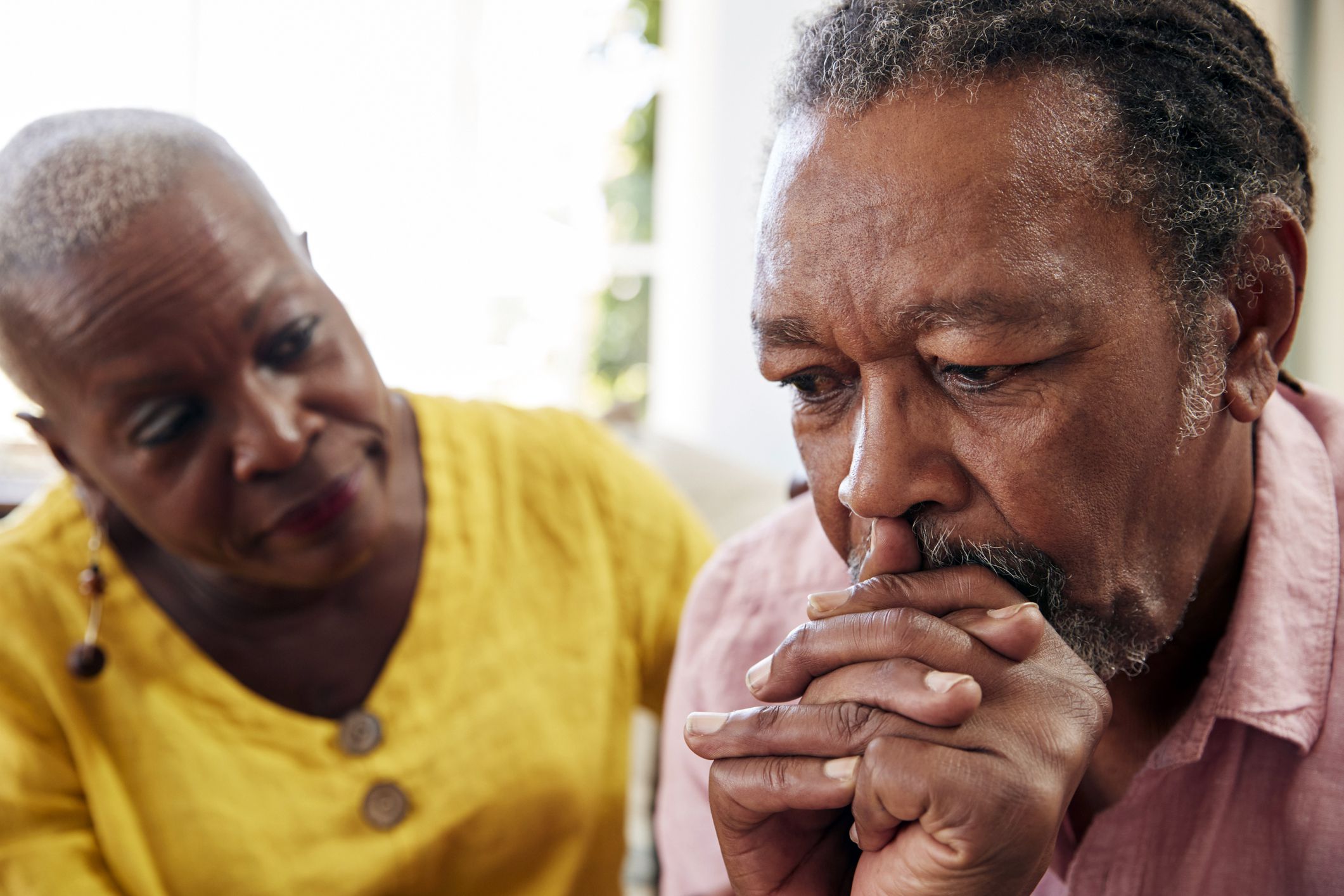 senior man looking serious and sad with concerned senior woman in background