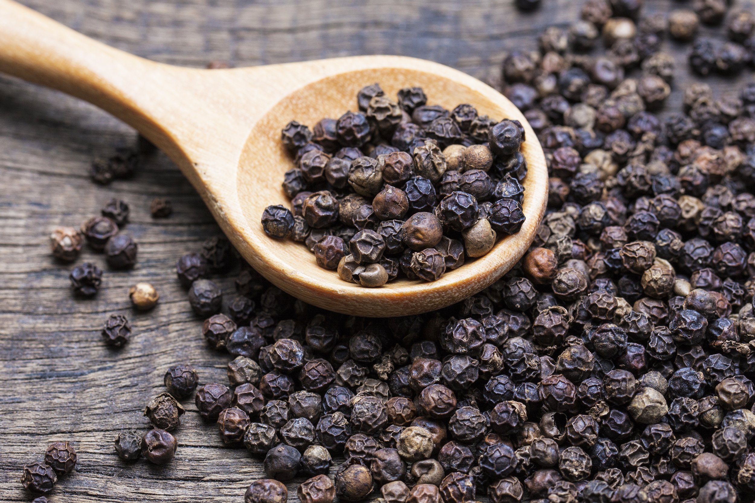 milled black peppercorns on table