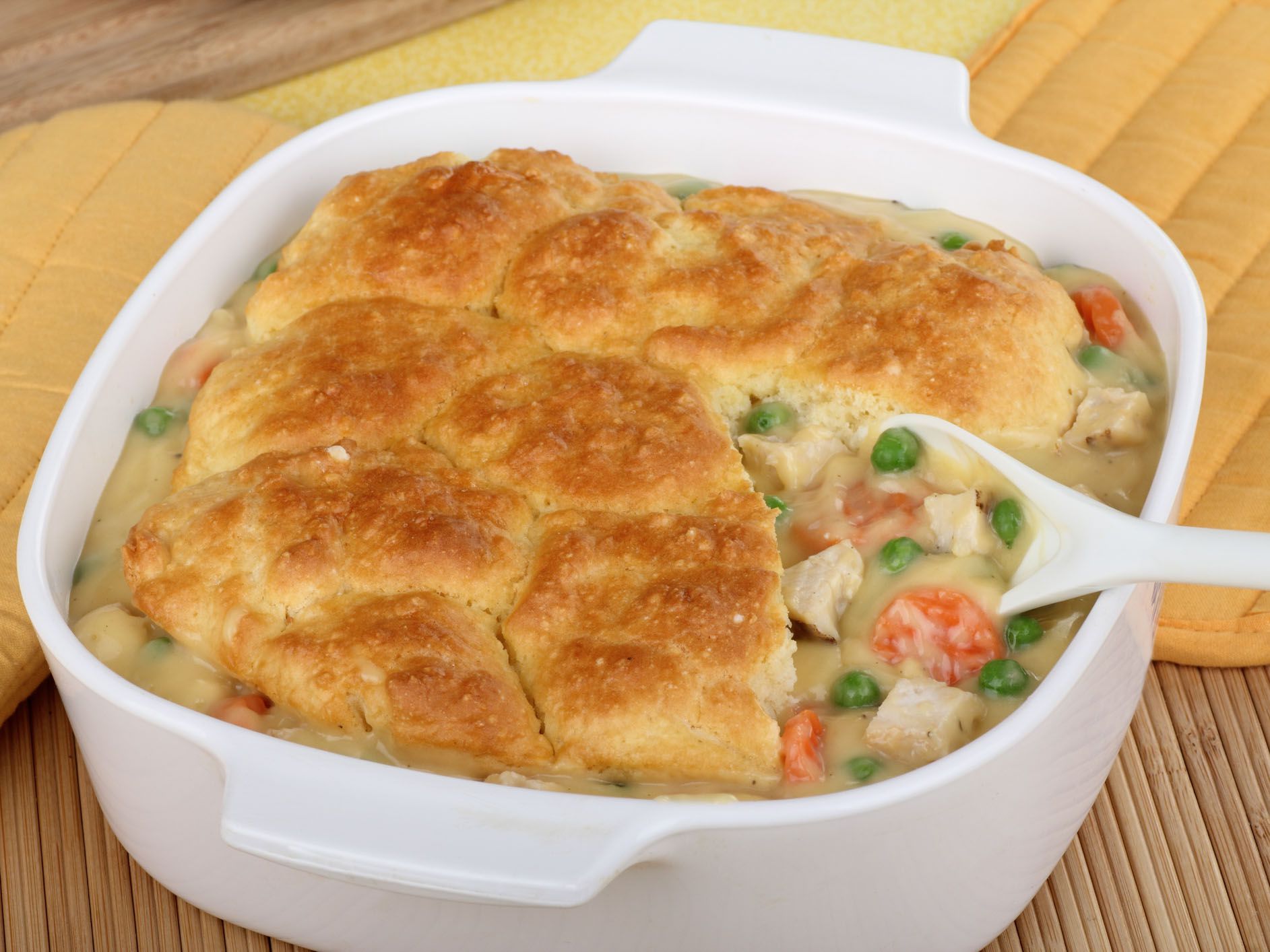 Chicken pot pie with carrots and peas in white ceramic serving dish