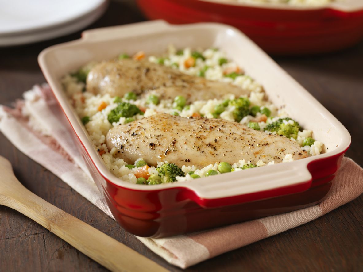 Chicken and rice casserole in red rectangular baking dish on white and brown checkered towel on a wood table