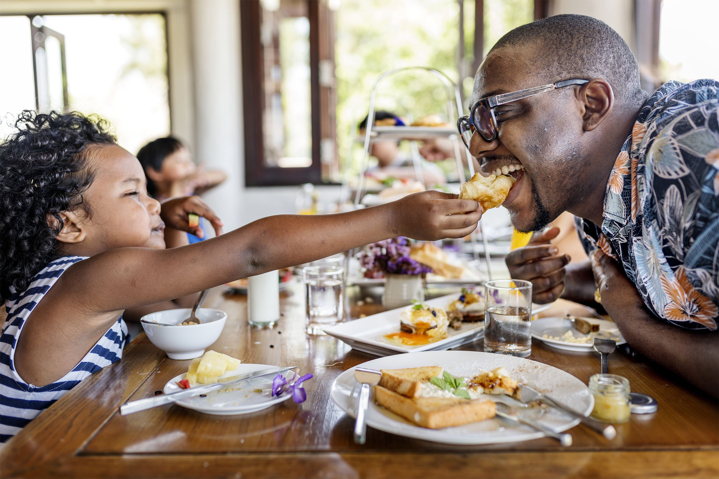 Child feeding father at a restaurant