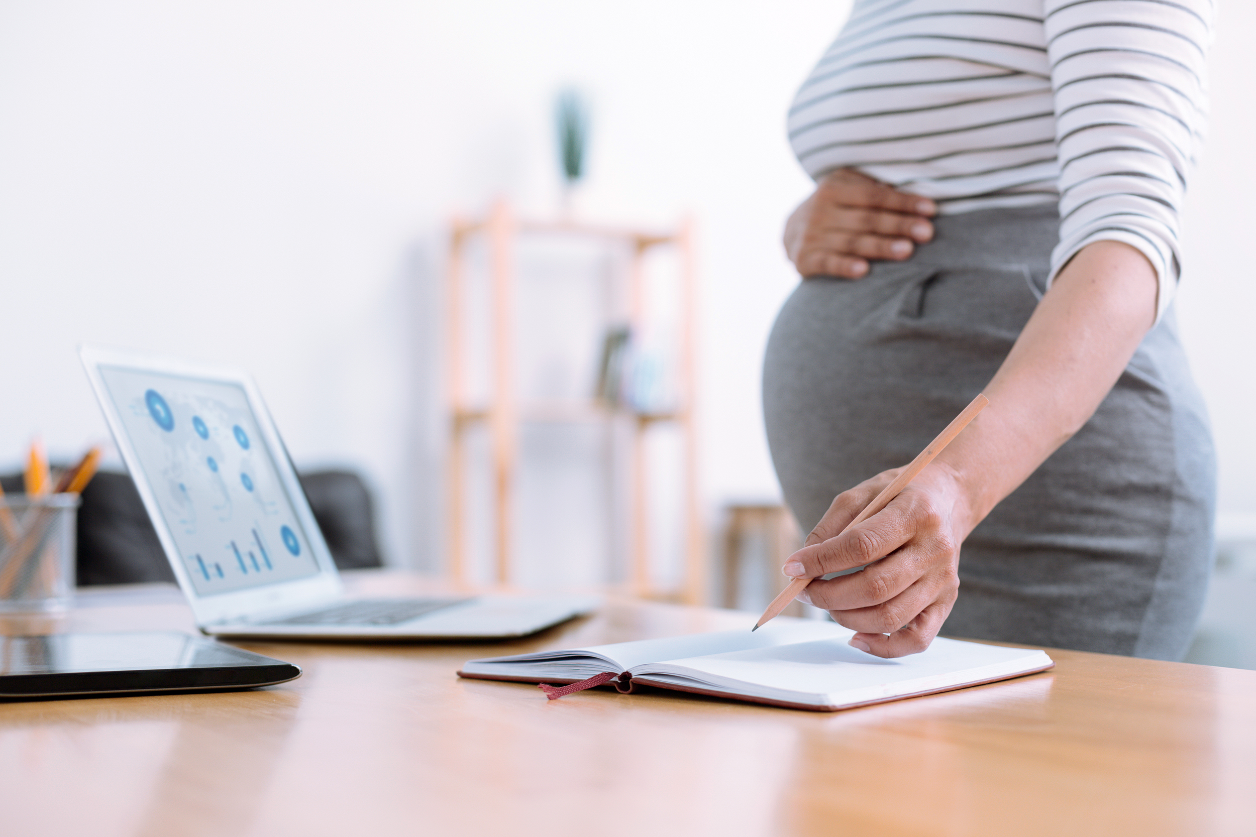 Pregnant woman standing up from her desk