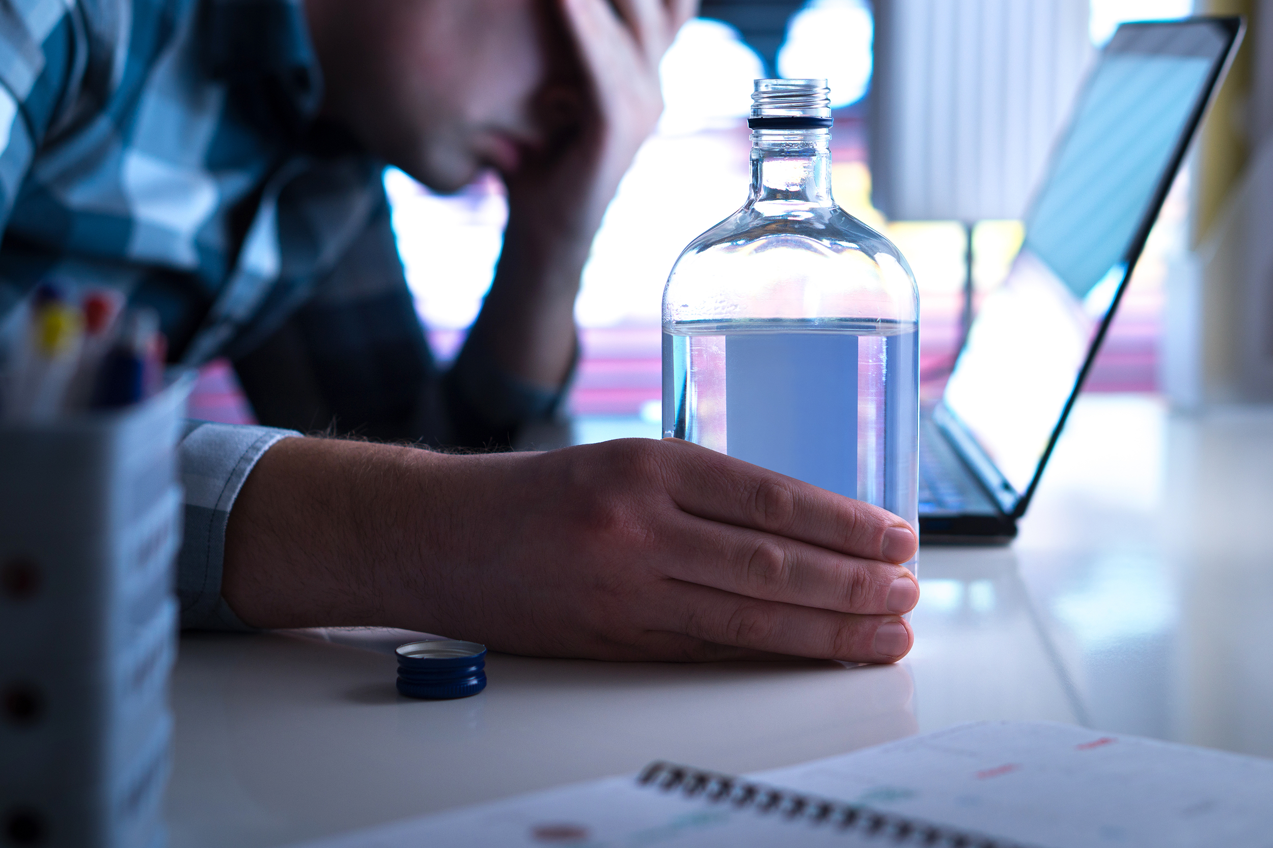 Man drinking alcohol at his desk at work