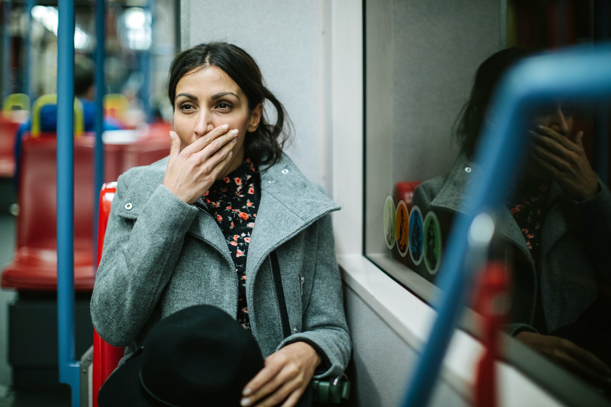 woman yawning and touching her face on public transport