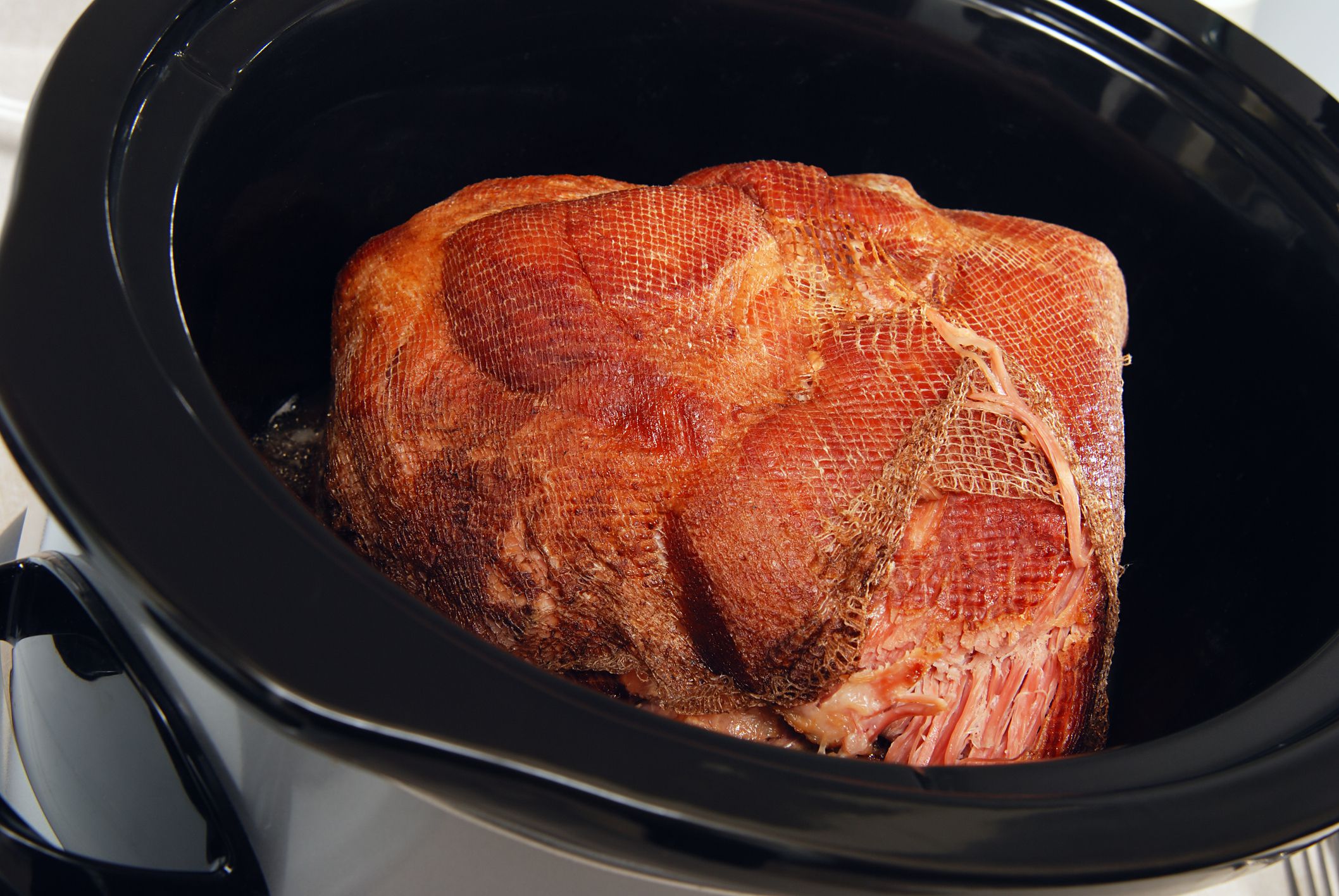 Big piece of ham cooking slowly in a crock pot