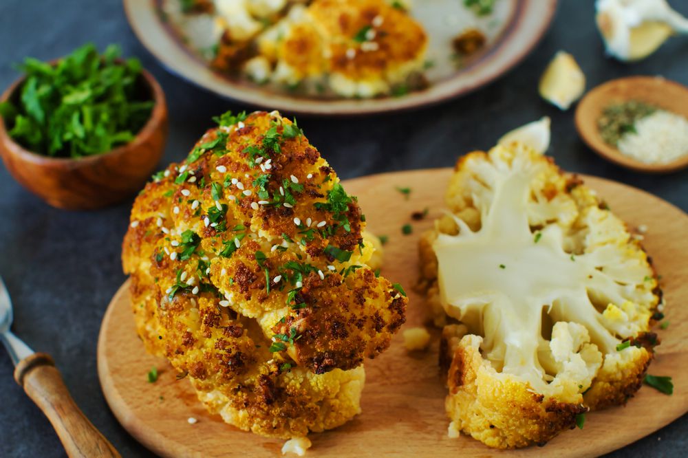 One whole roasted cauliflower head with seeds and parsley
