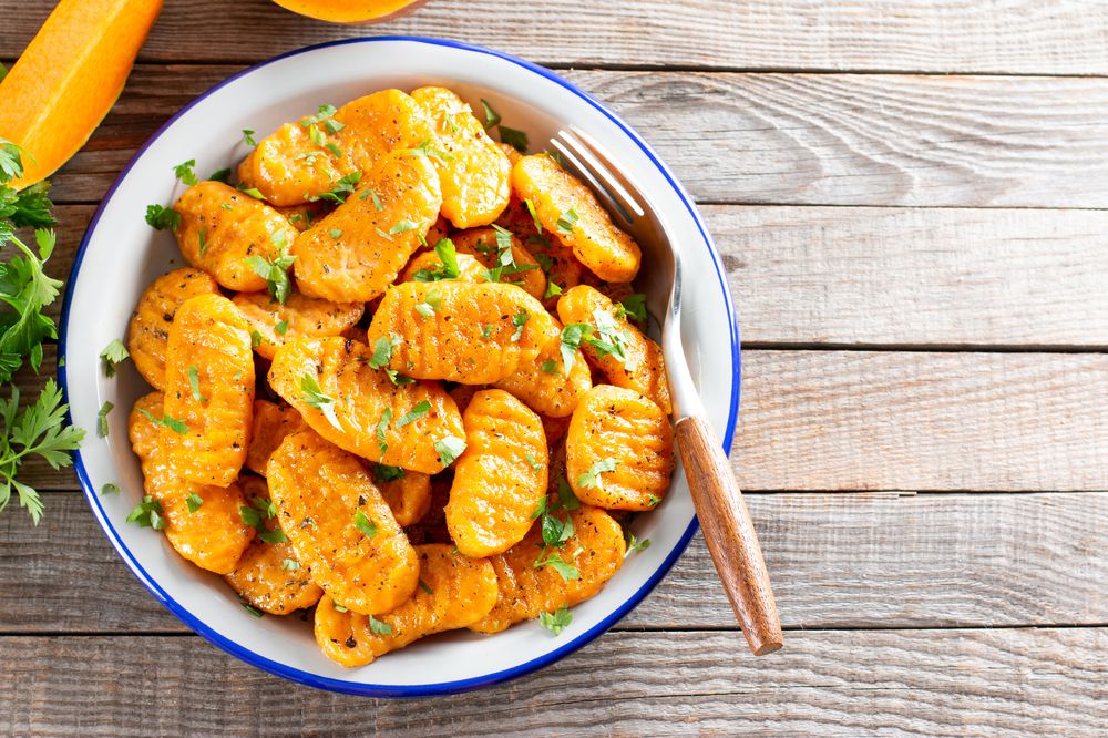 Gnocchi with a pumpkin on the plate. Italian dumplings with butter. Top view, copy space