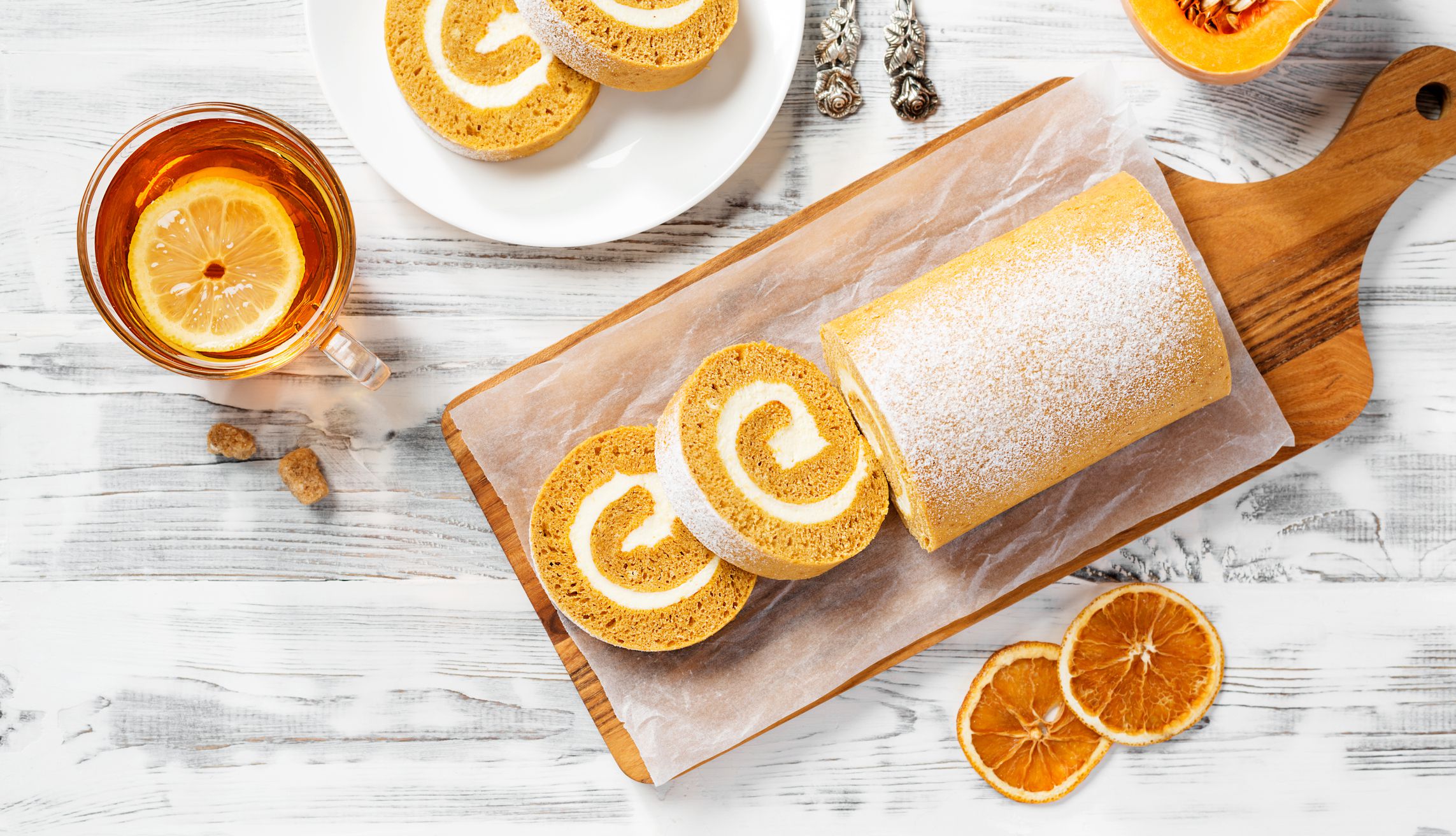 Pumpkin Cake Roll with Cream Cheese Filling. Autumn Baking. White wooden background, top view