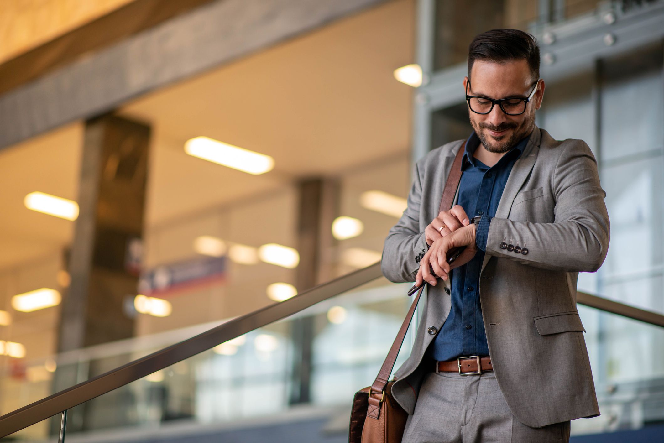 Image of a young businessman checking the time on his wrist watch.
