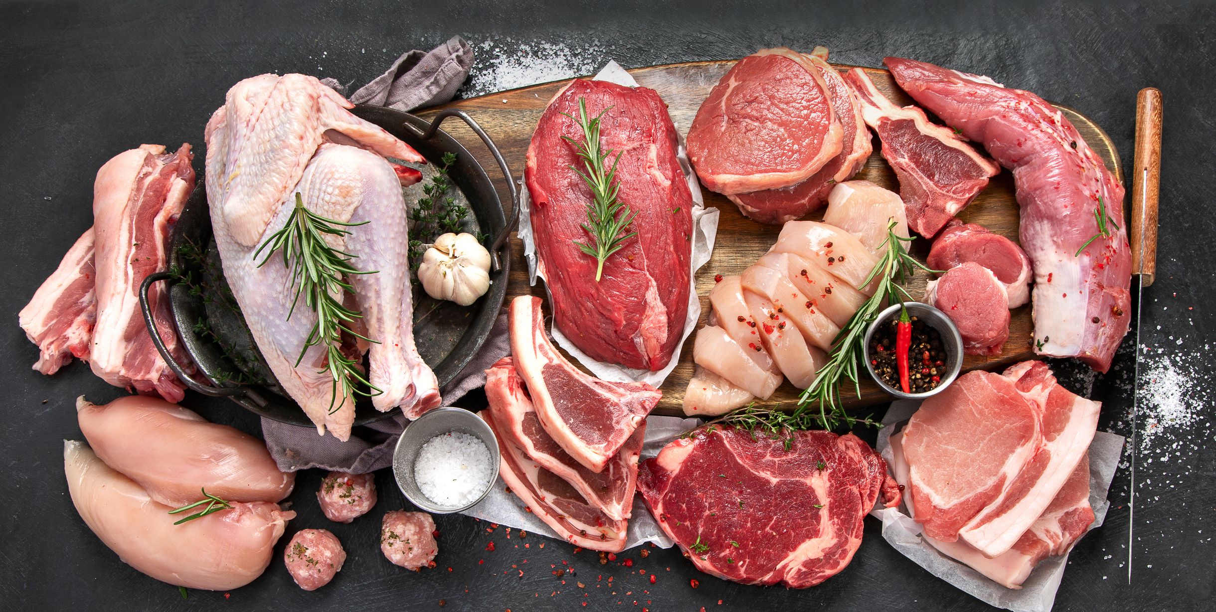 Different types of raw meat - beef, pork, lamb, chicken on dark background. Top view, copy space
