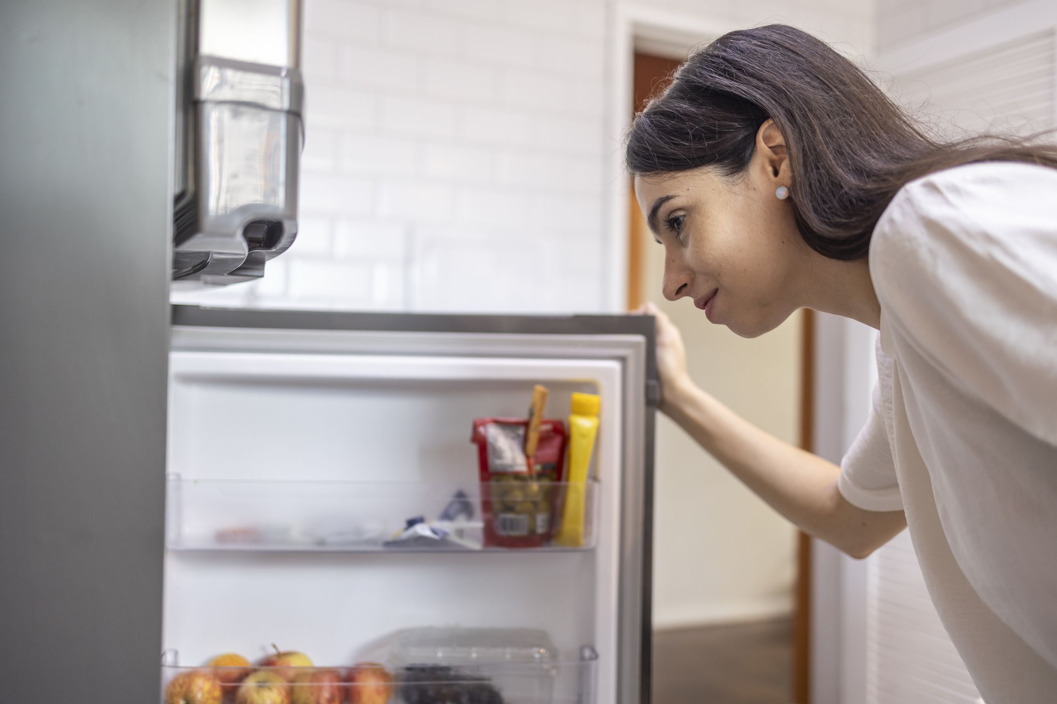 Caucasian woman opening the fridge in the kitchen