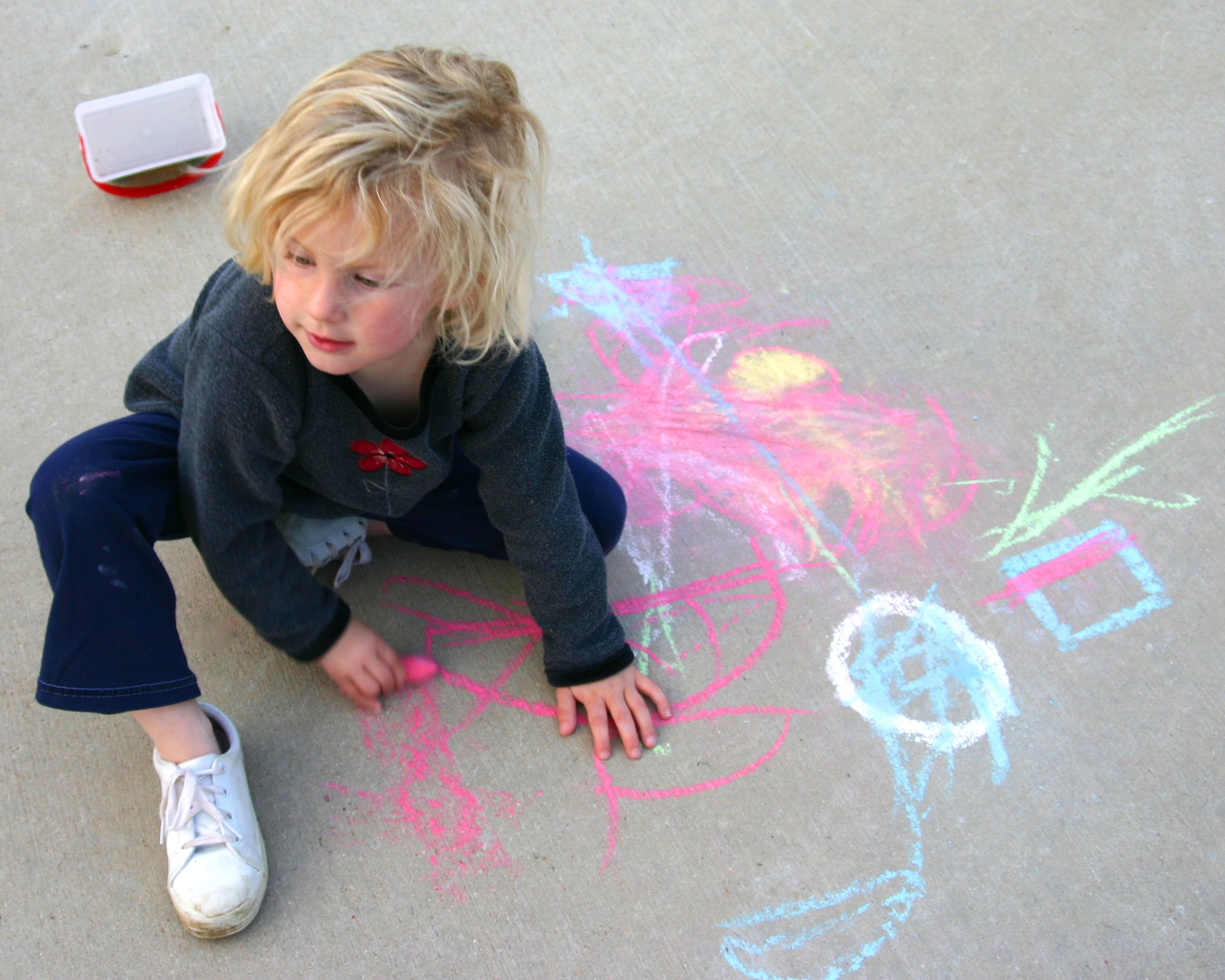 child drawing with chalk on sidewalk