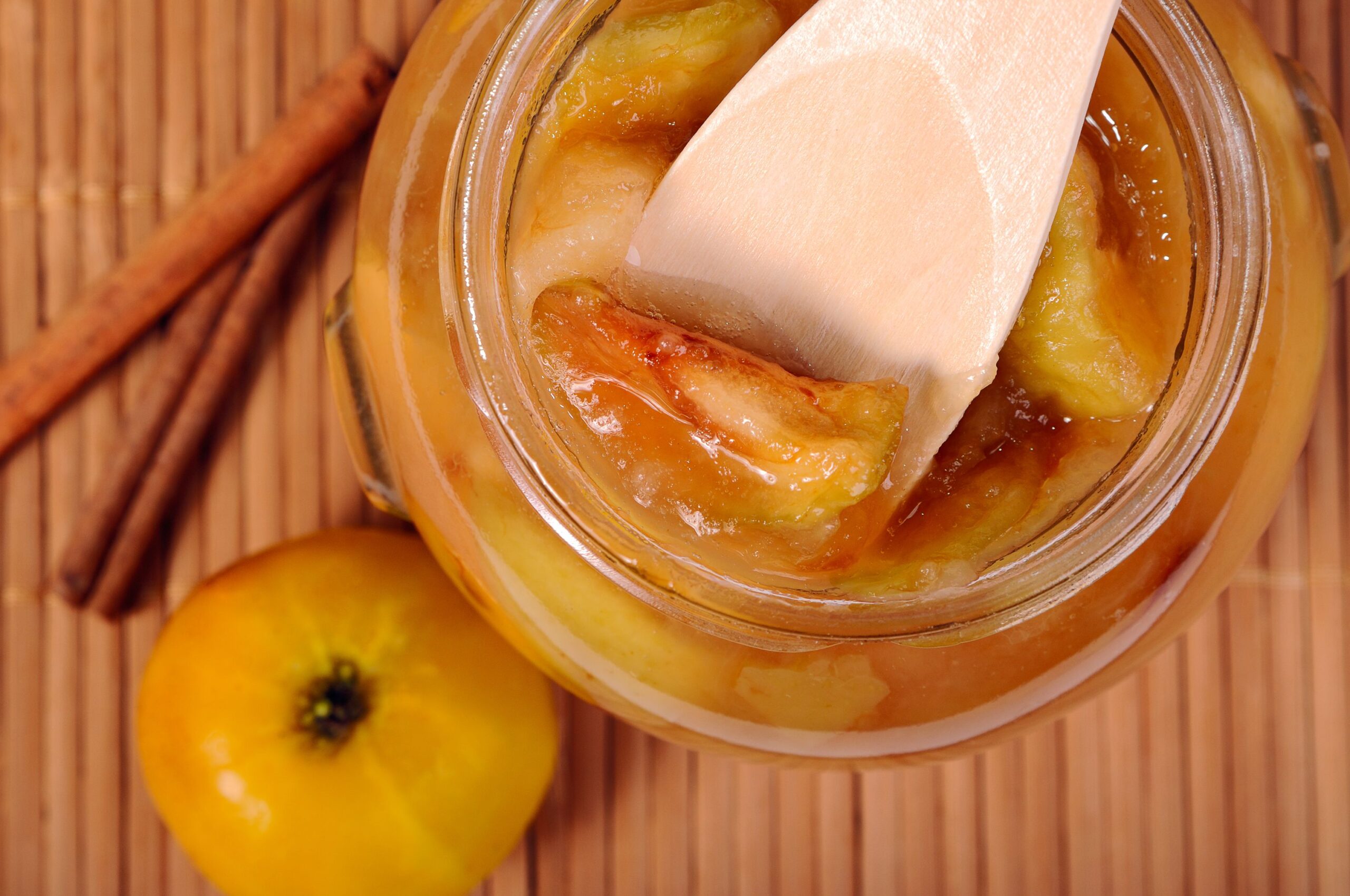 Wooden spoon in the jar of apple jam closeup