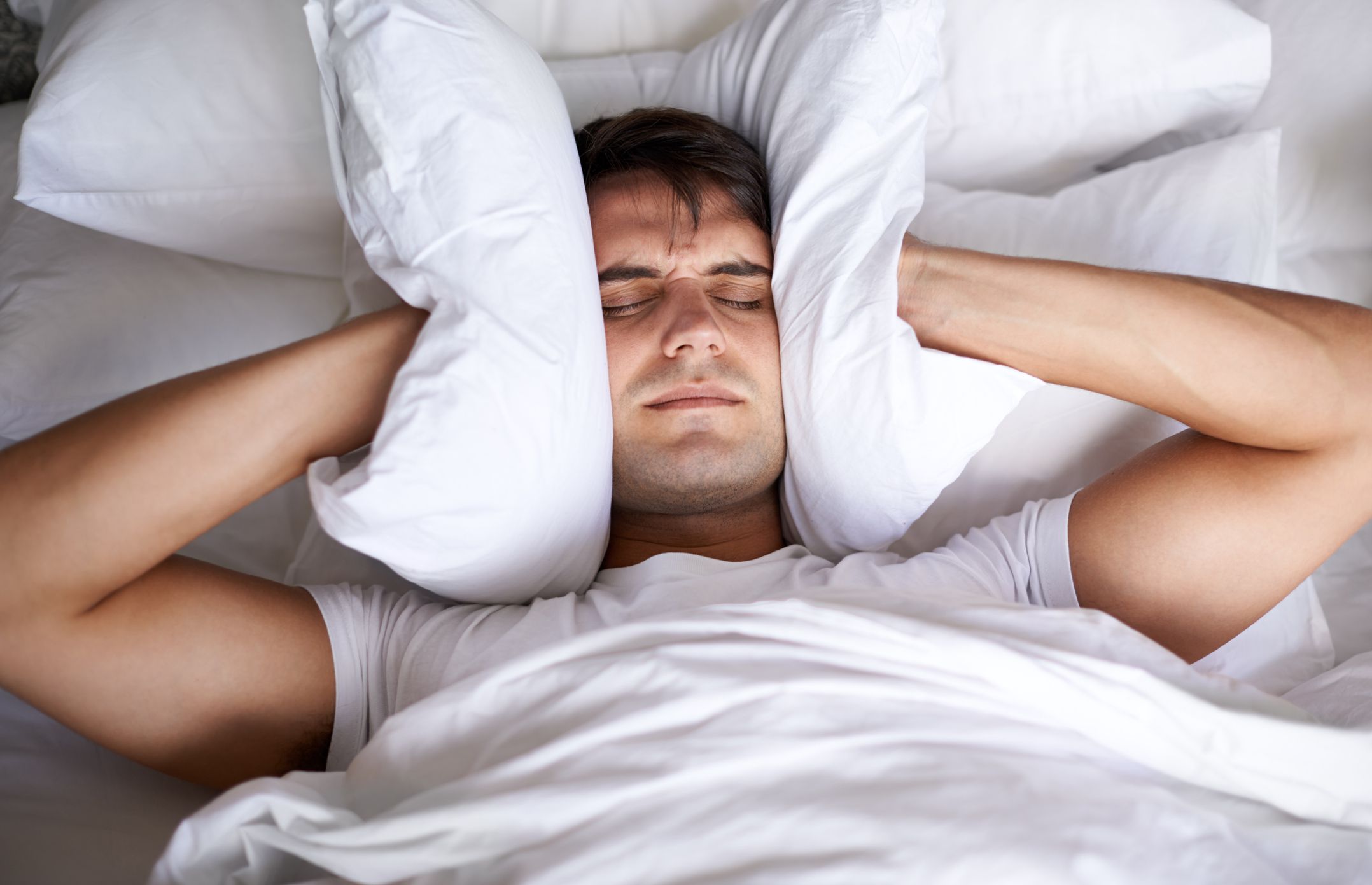 Cropped shot of a young man covering his ears with a pillow while trying to sleephttp://195.154.178.81/DATA/i_collage/pi/shoots/783486.jpg