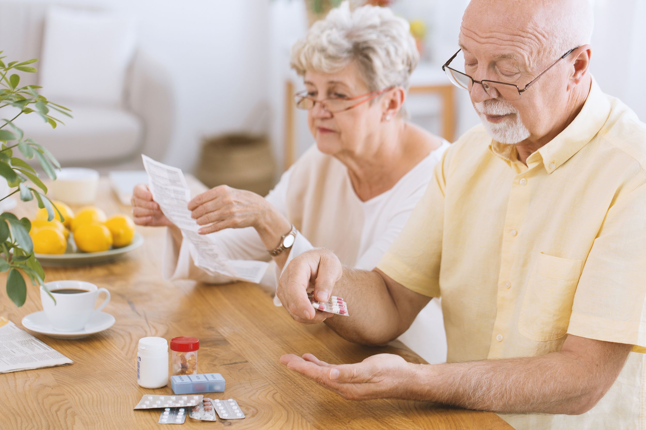 senior man taking medicament while wife is looking over side affects