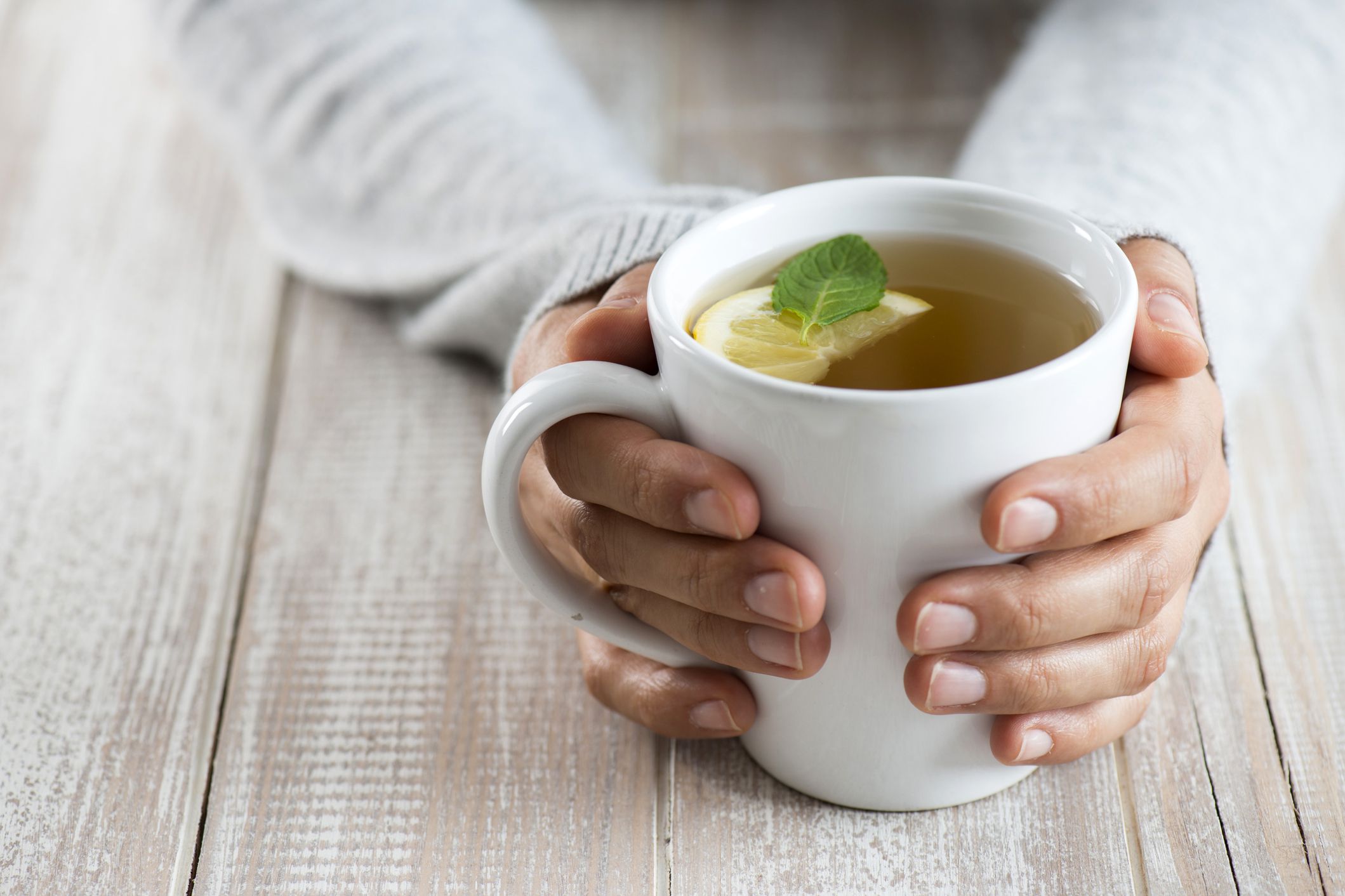 hands holding tea mug with lemon