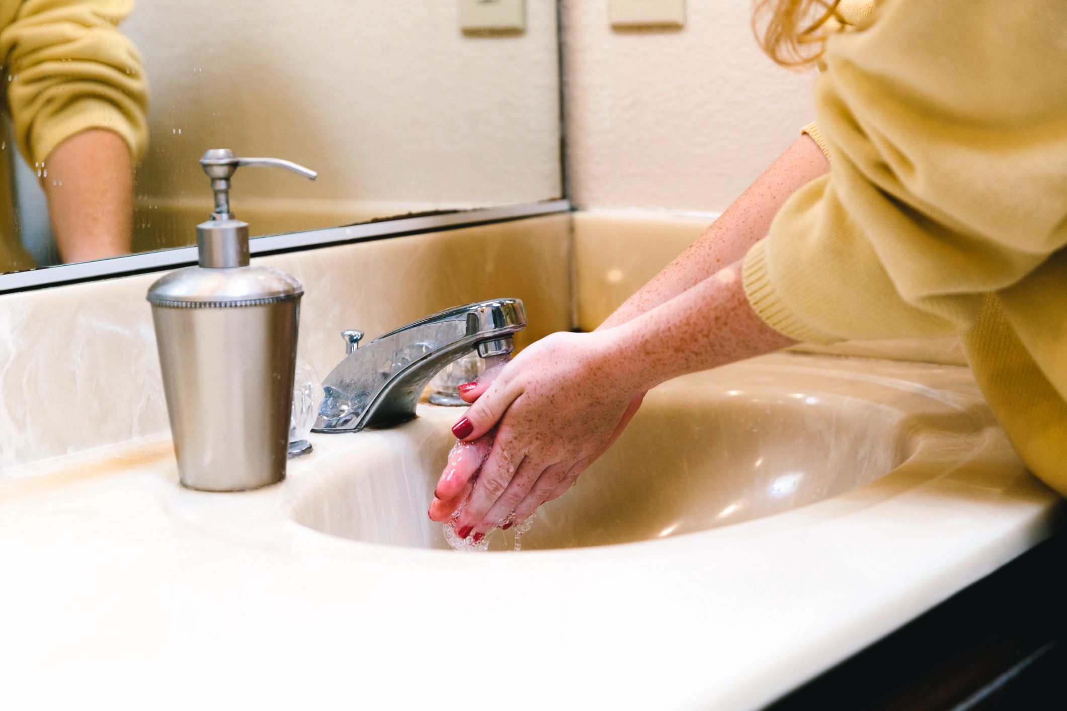 close-up of woman washing hands in home bathroom with soap