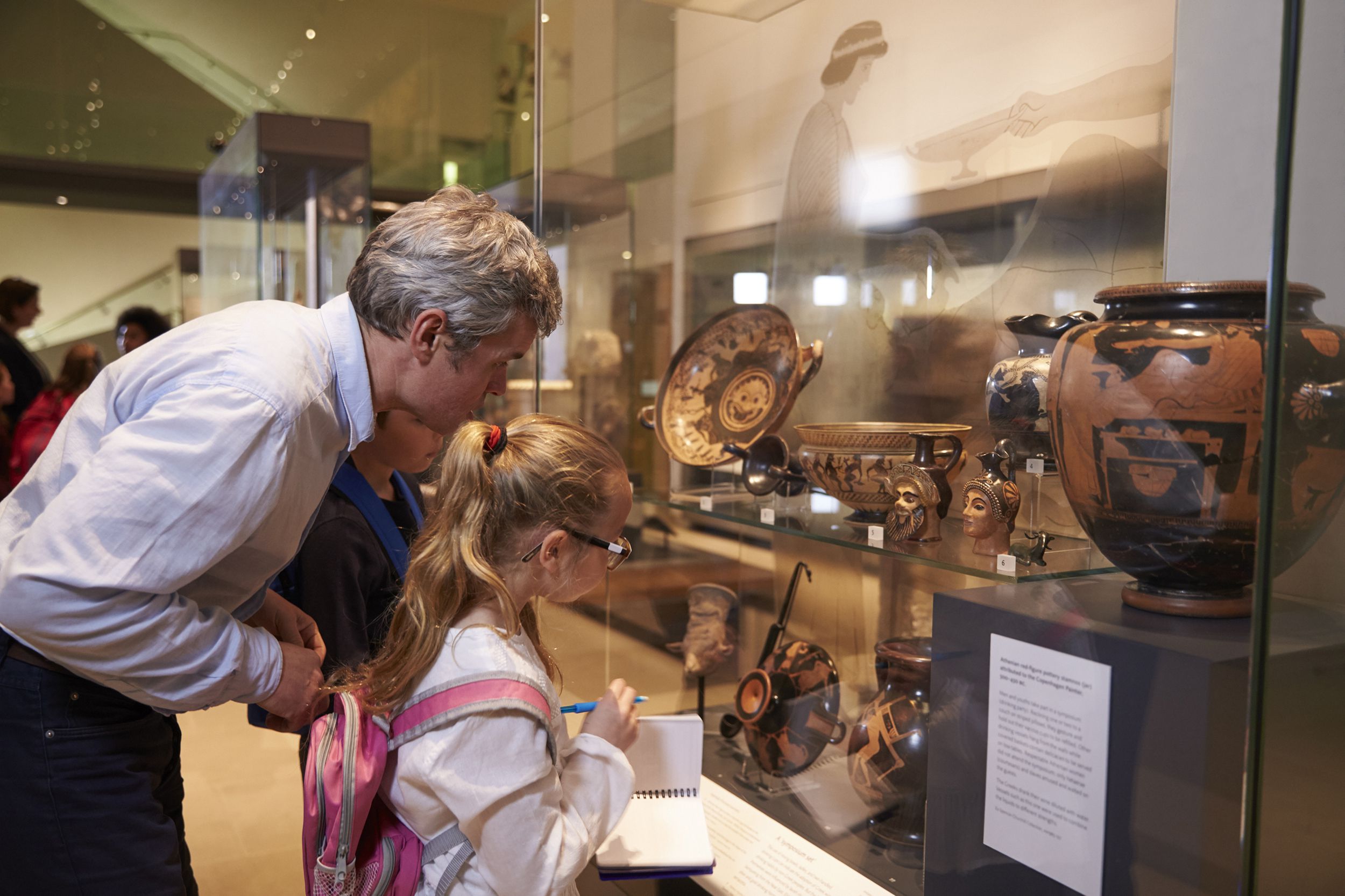 teacher and pupils looking at artifacts on display in museum