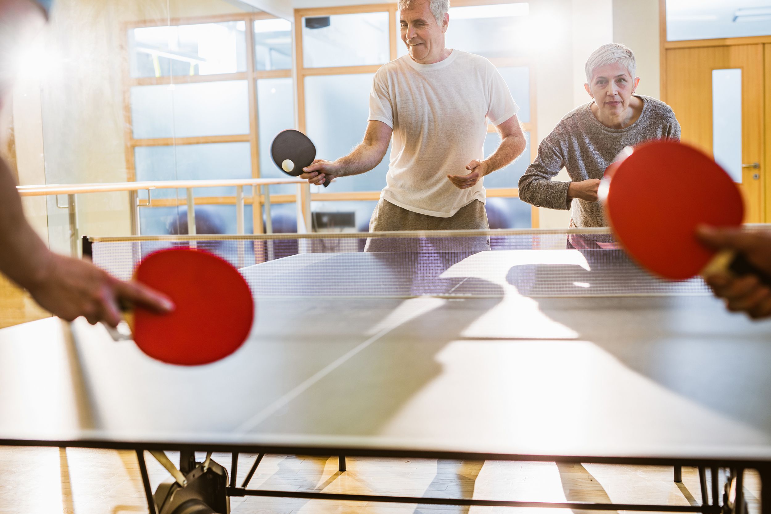 group of active seniors playing table tennis in a health club