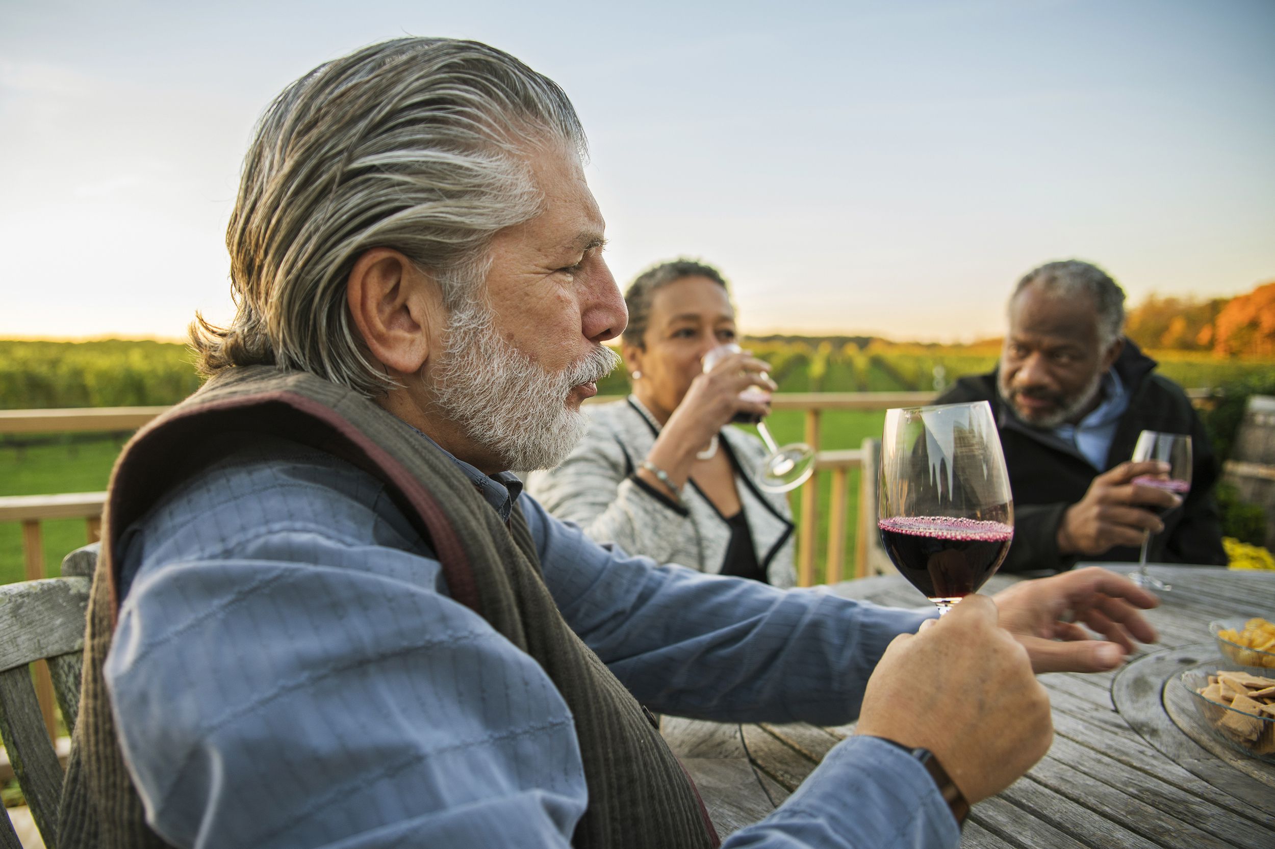 three senior friends drinking the red wine at the winery