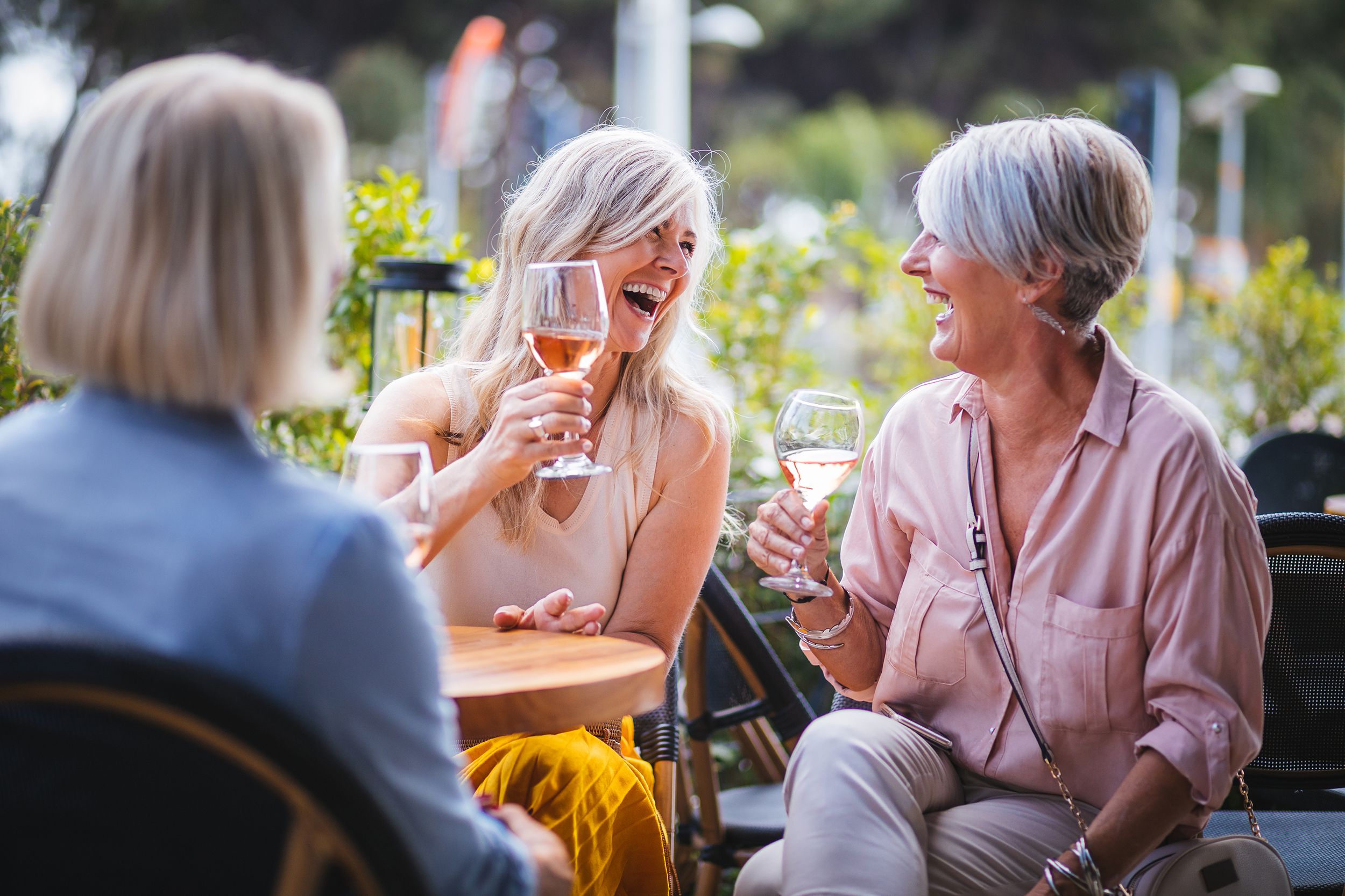 happy senior women drinking wine and laughing together at restaurant