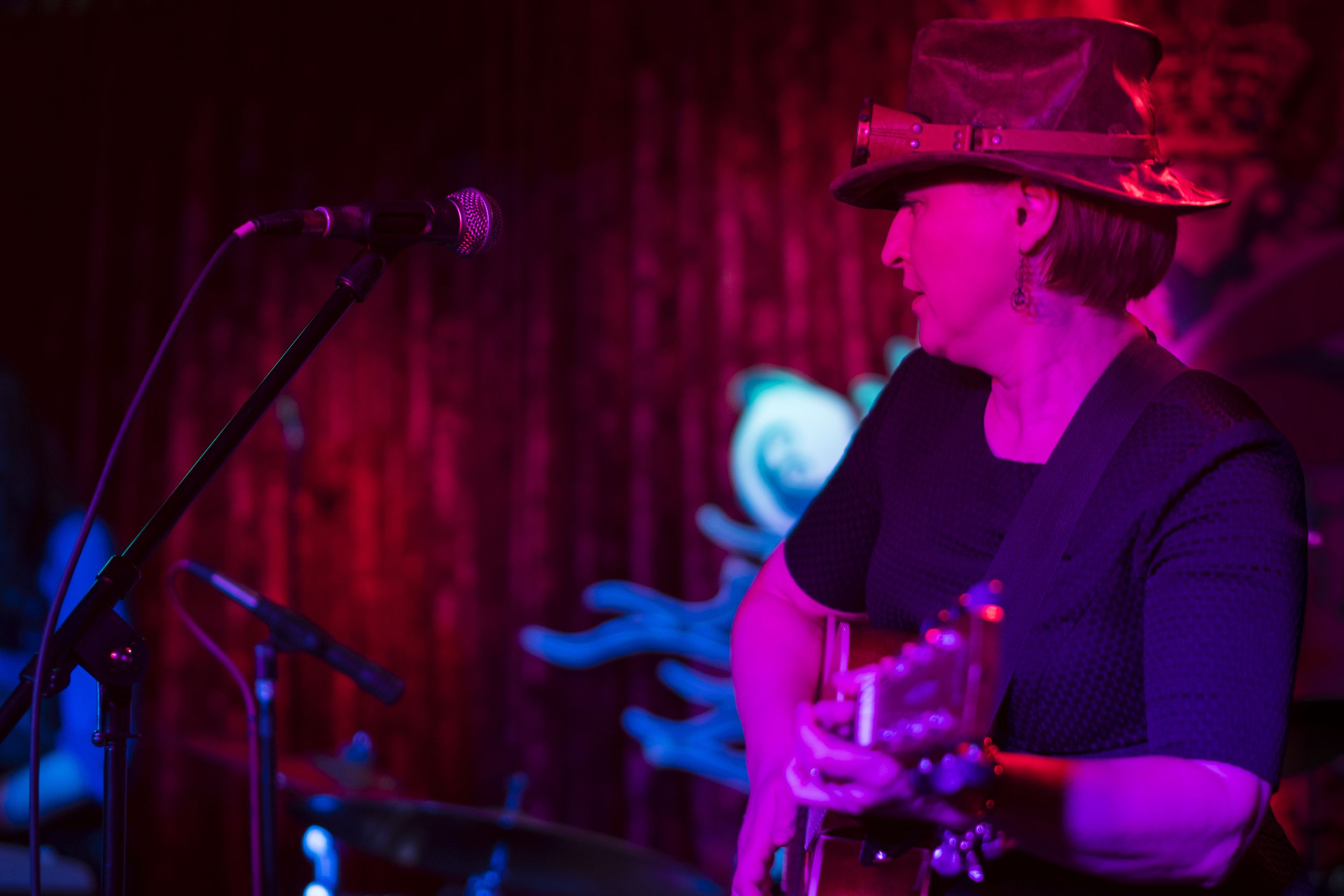 middle-aged woman playing guitar in rock band on stage at a bar