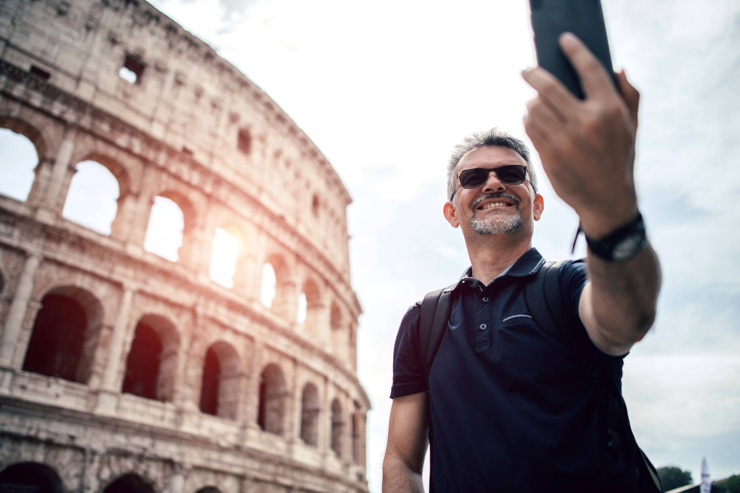 senior man taking selfie with Rome monuments in the background