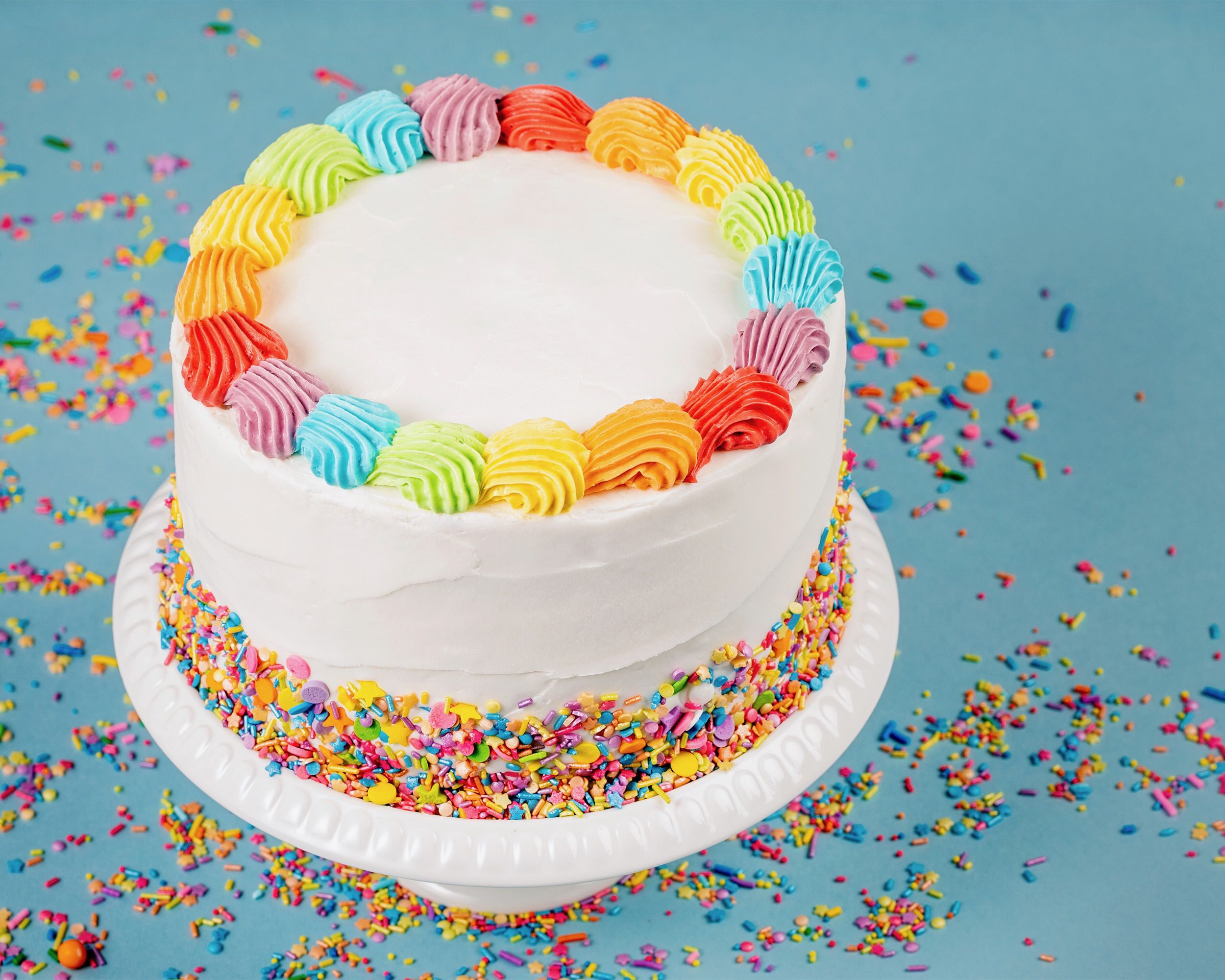 Cake with white frosting and multicolored decorations on a blue tablecloth