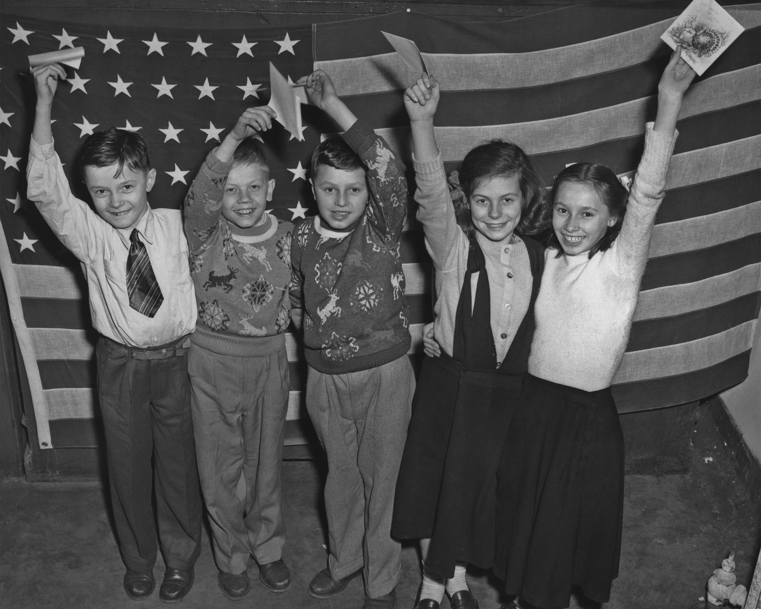 A group of boys and girls, all displaced persons from Europe, waving their invitations to a Thanksgiving party held at the Tavern on the Green, Central Park