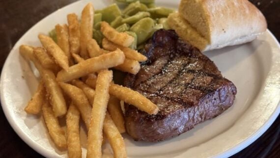 A plate of food featuring a juicy steak and golden french fries, just like the classic fare served at many cheap steak restaurants.