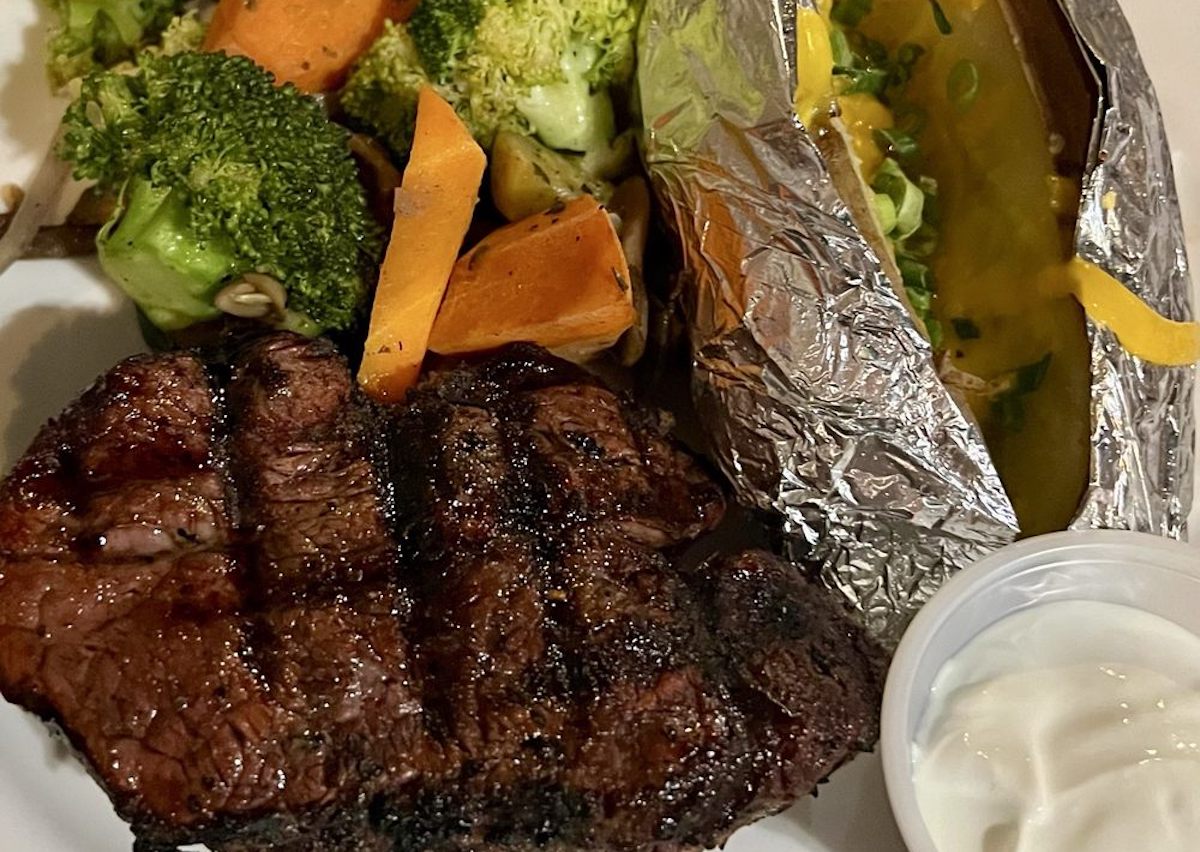 Grilled steak with char marks, baked potato in foil topped with melted cheese and chives, steamed broccoli and carrots, and a side of sour cream—just like the comfort food classics you’ll find at cheap steak restaurants.