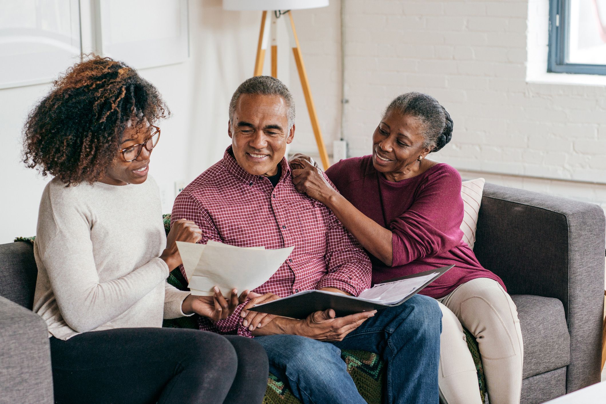mature couple speaking to financial advisor, sitting on couch