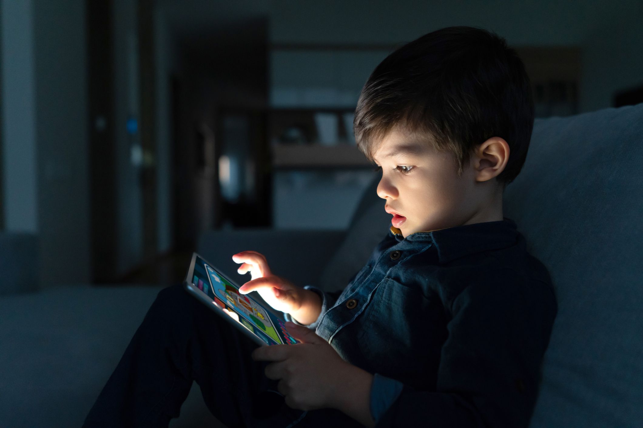 Portrait of a young boy using an app on a digital tablet at home at nighttime â lifestyle