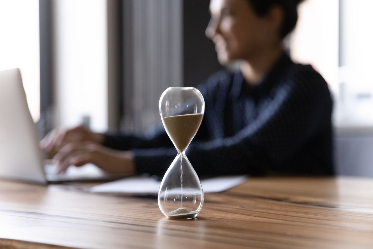 A sand timer placed on a nice work desk.