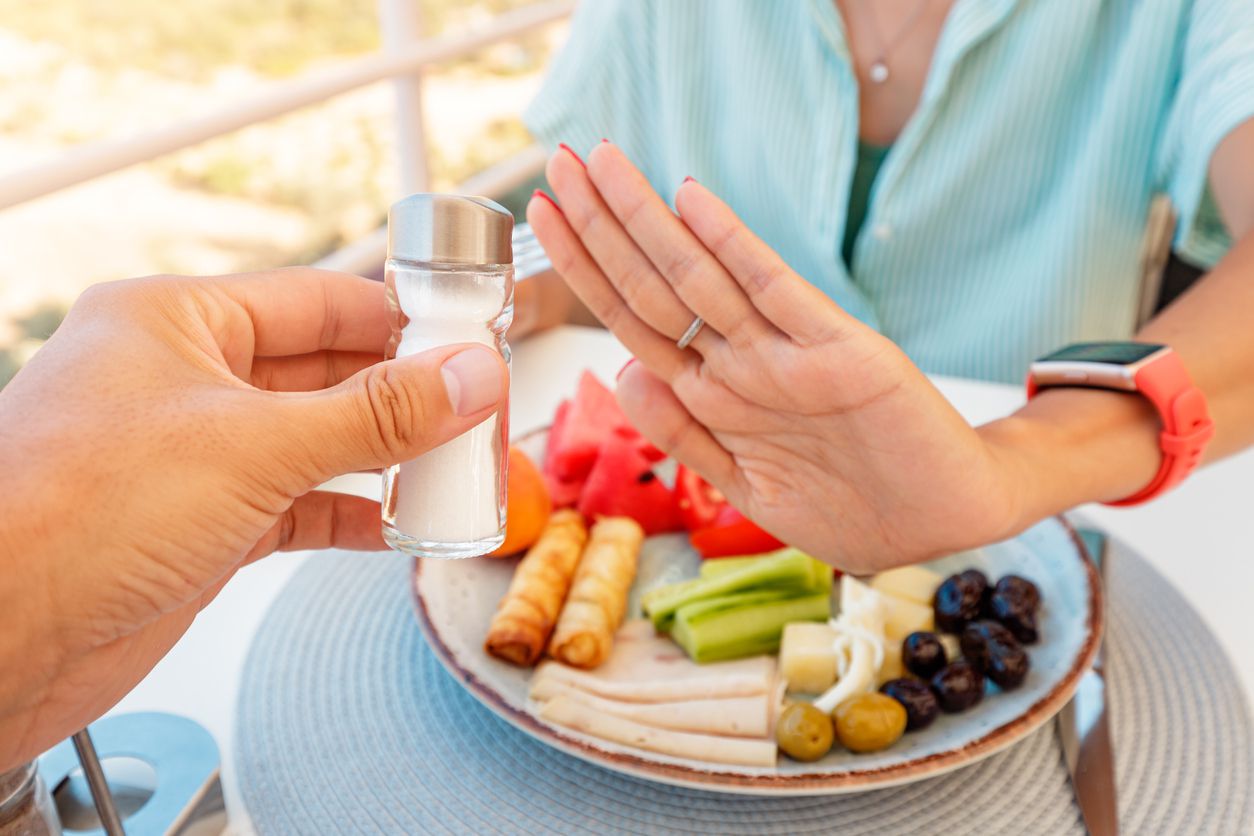 An image of a customer putting their hand up to refuse more salt on their food.