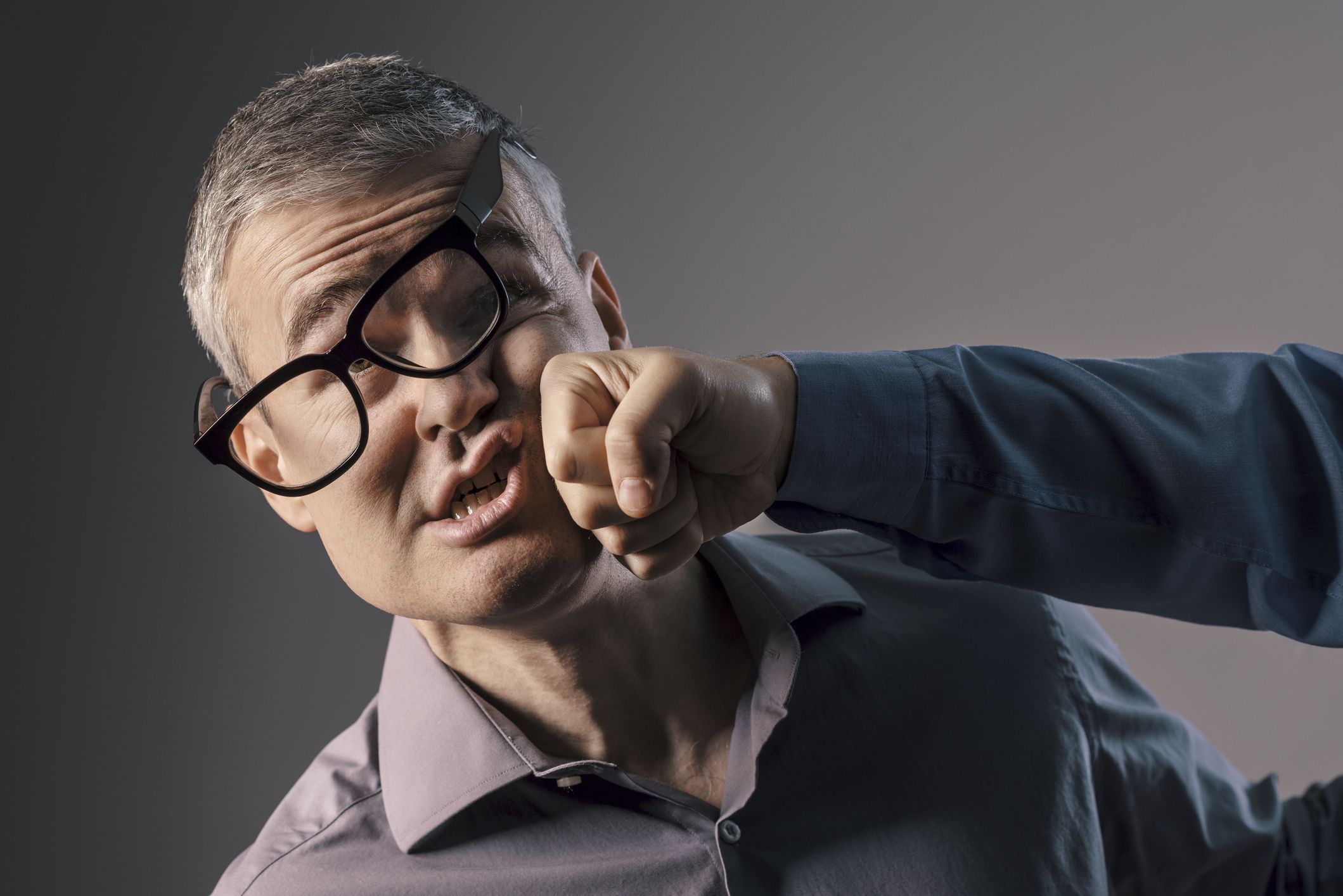 Man with glasses getting hit by a punch, violence and fight concept